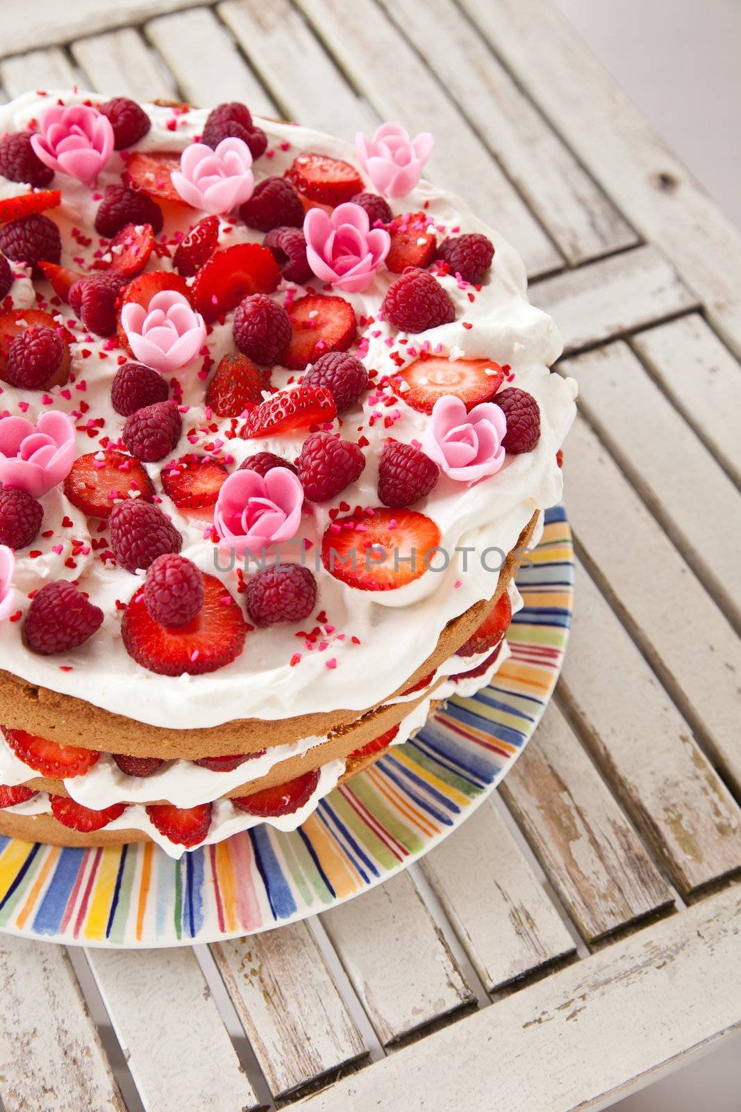 Delicious looking layered cake decorated with fruit, whipped cream and marizapan flowers