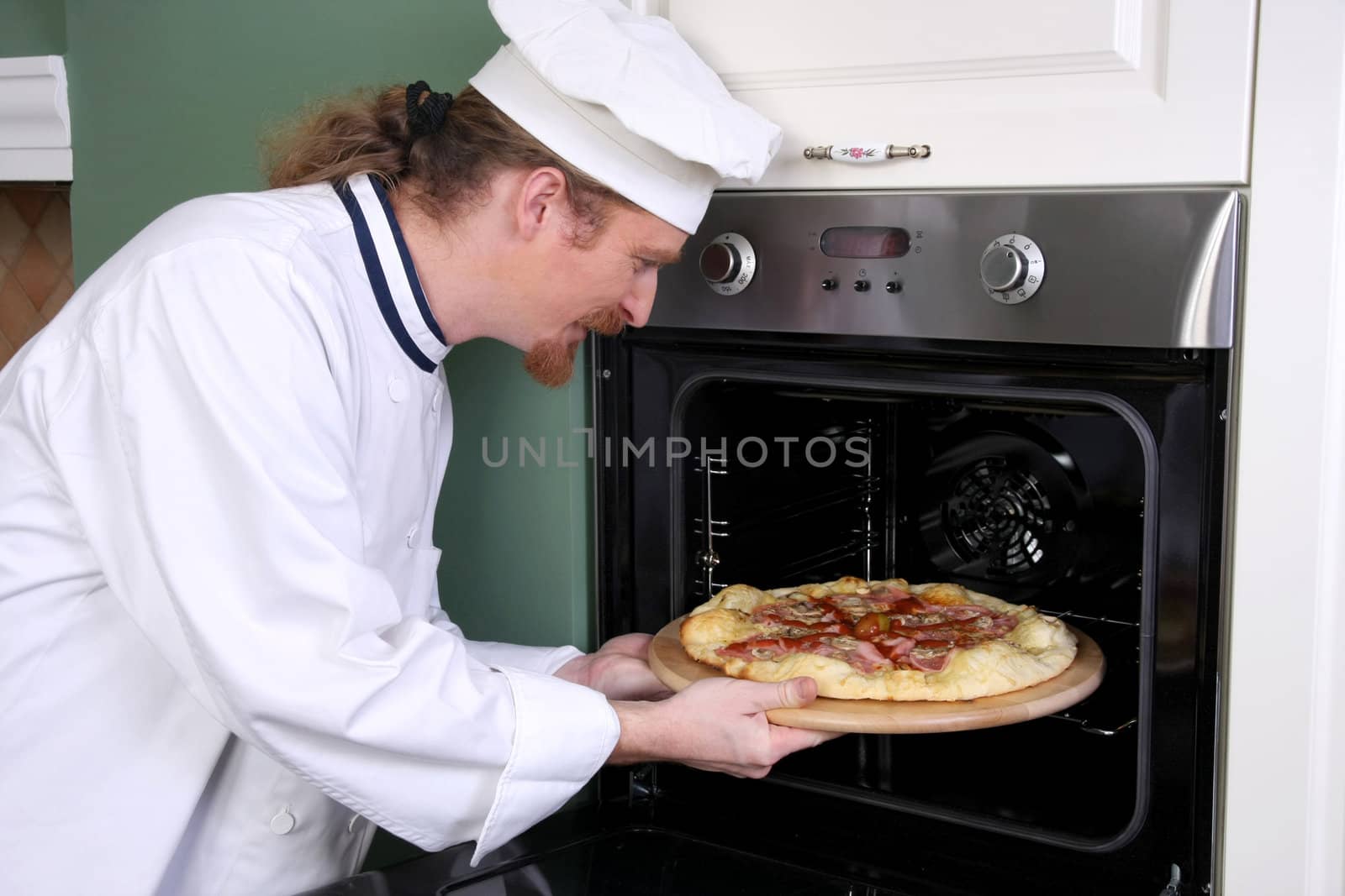 Young chef prepared italian pizza in kitchen  by vladacanon