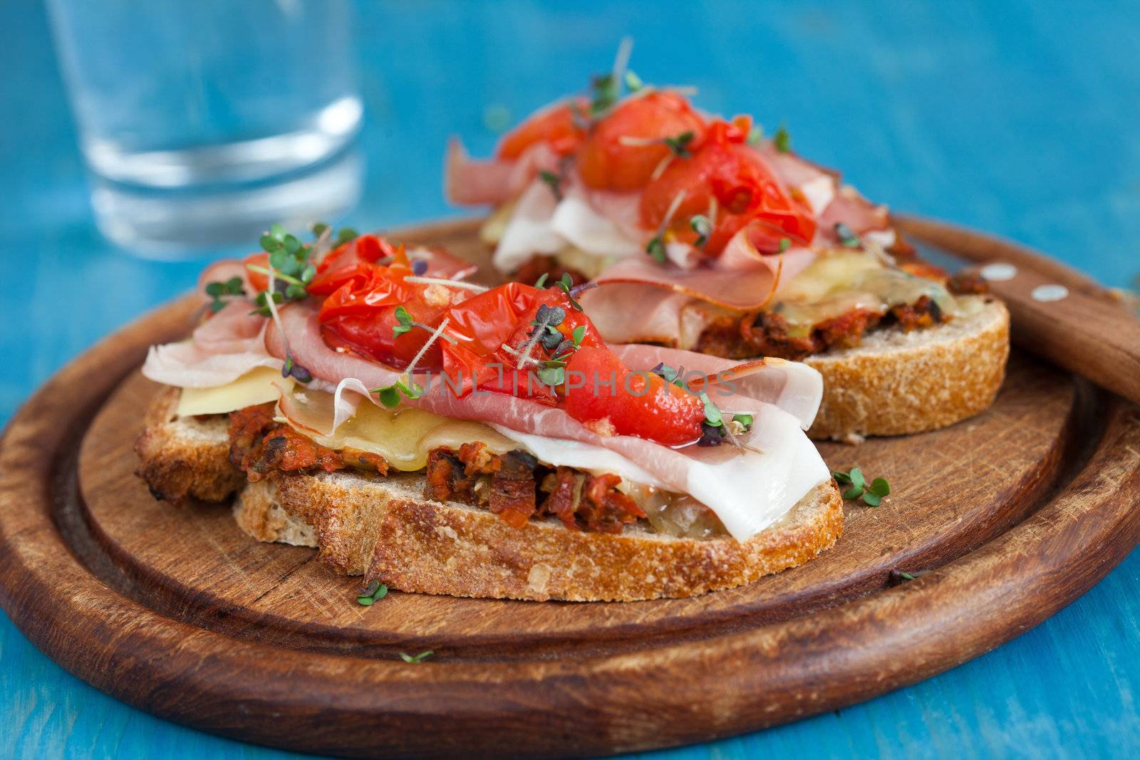 Delicious Italian bread dressed with grilled cheese and cherry tomatoes, ham, tapenade and mustard cress