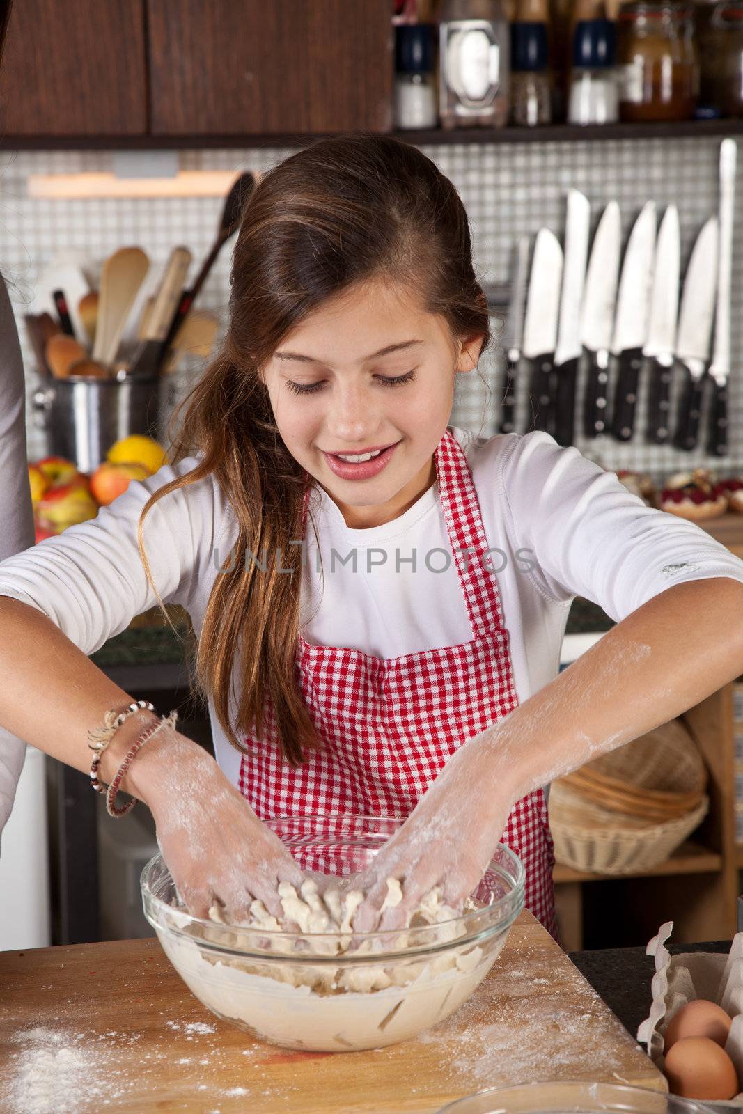 Young girl is kneading the dough in a bowl