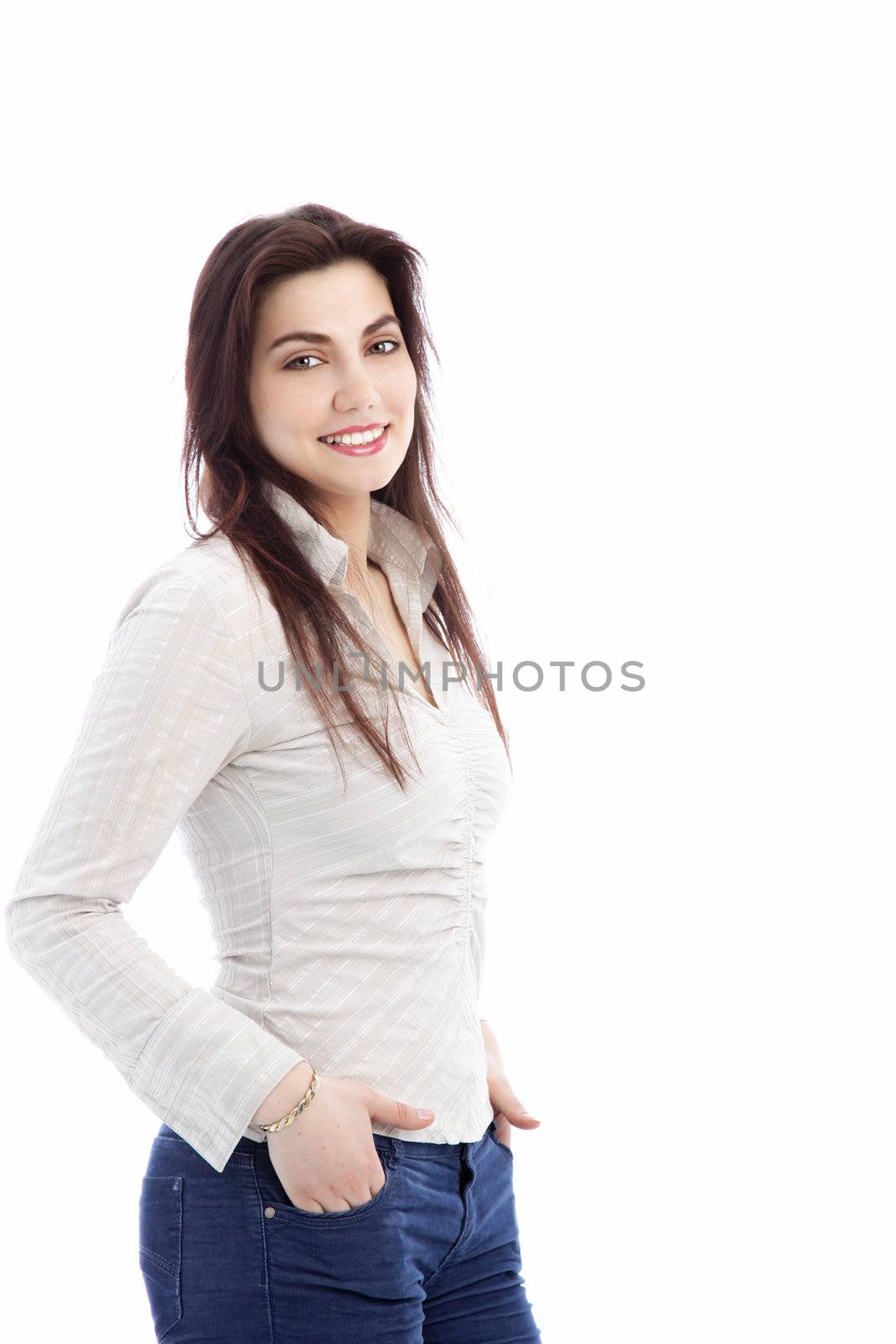 Smiling casual woman in jeans standing with her hands in her pockets smiling at the camera isolated on white