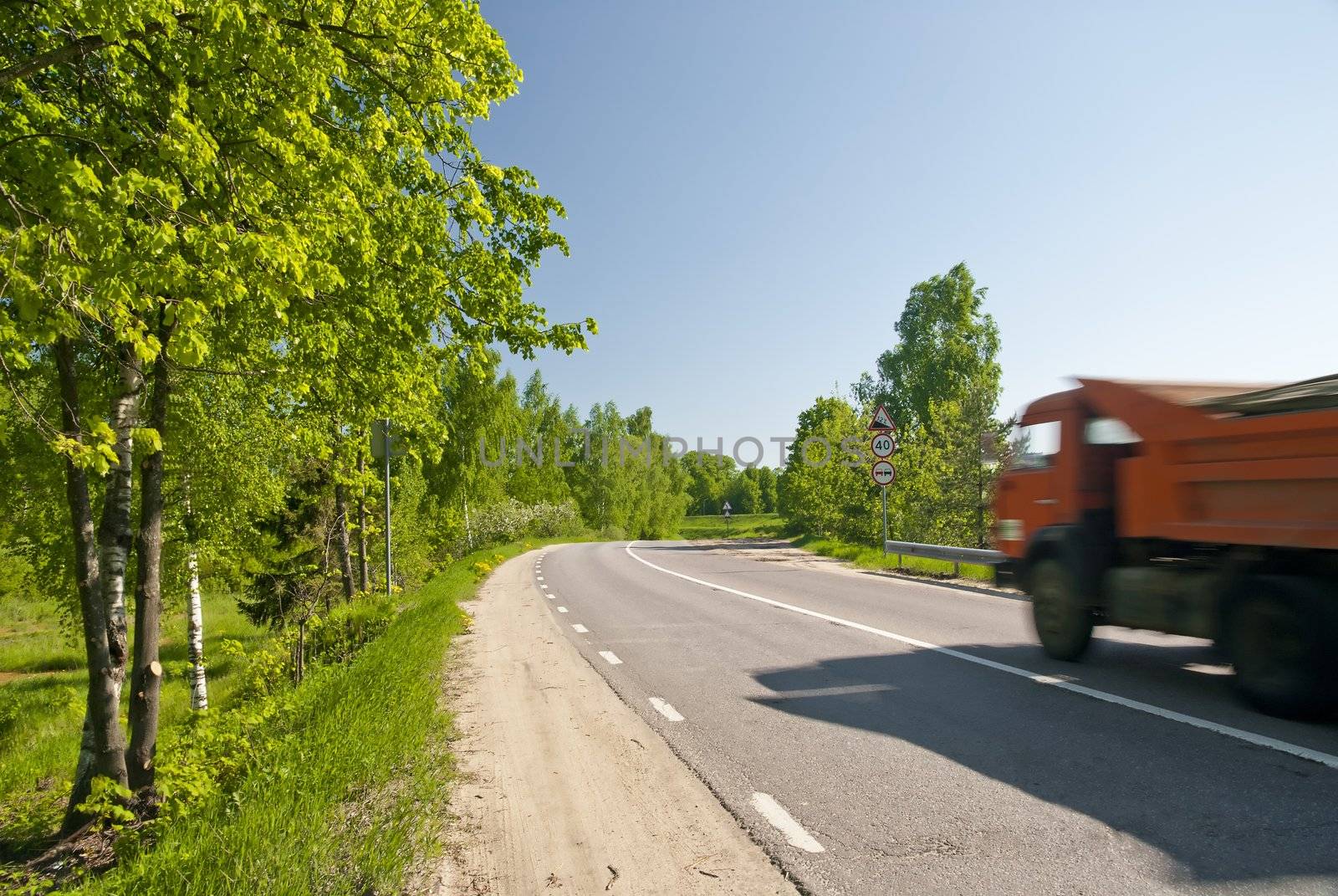 Dirt road with asphalt dump truck in motion