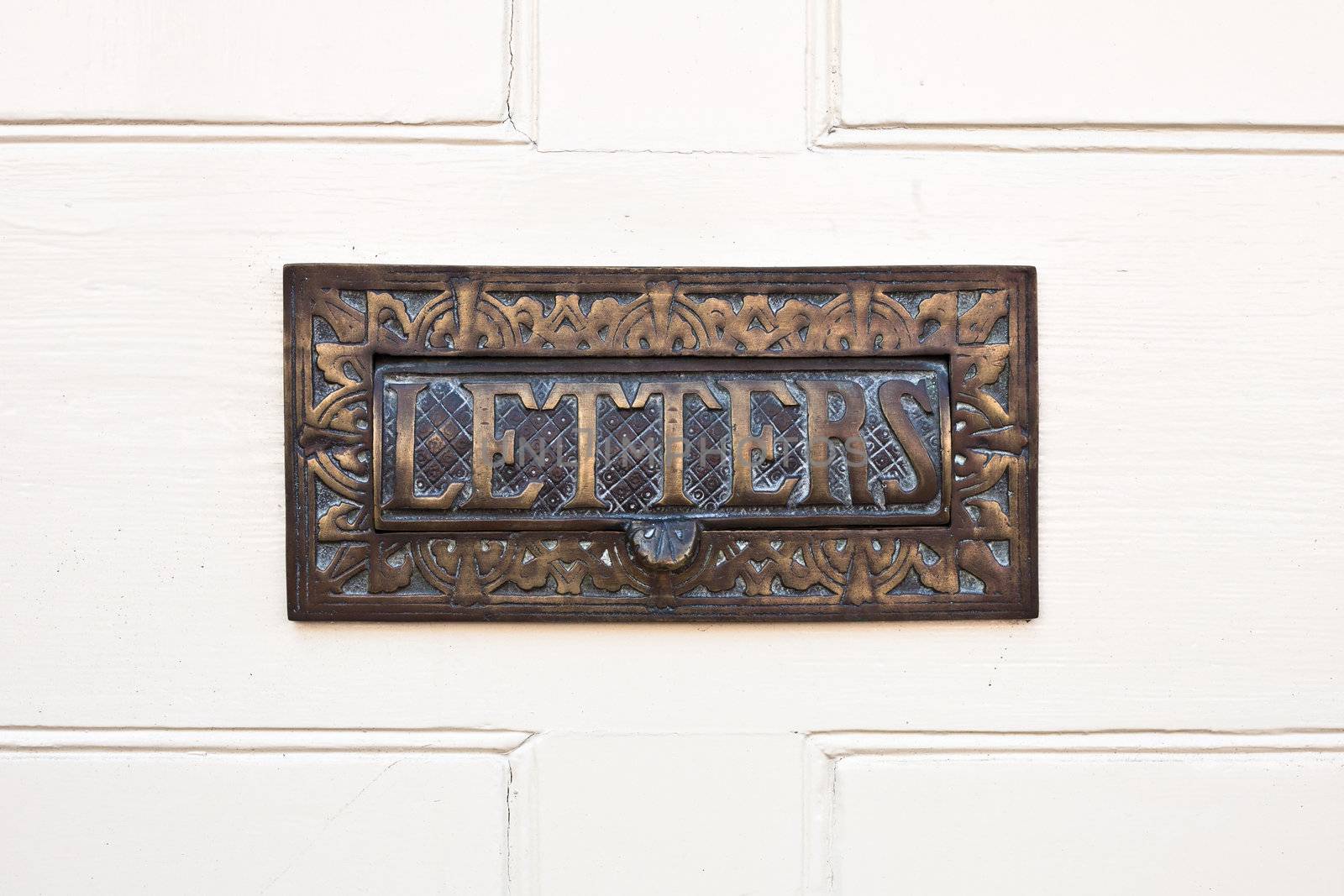 Ornate letterbox in a white wooden door