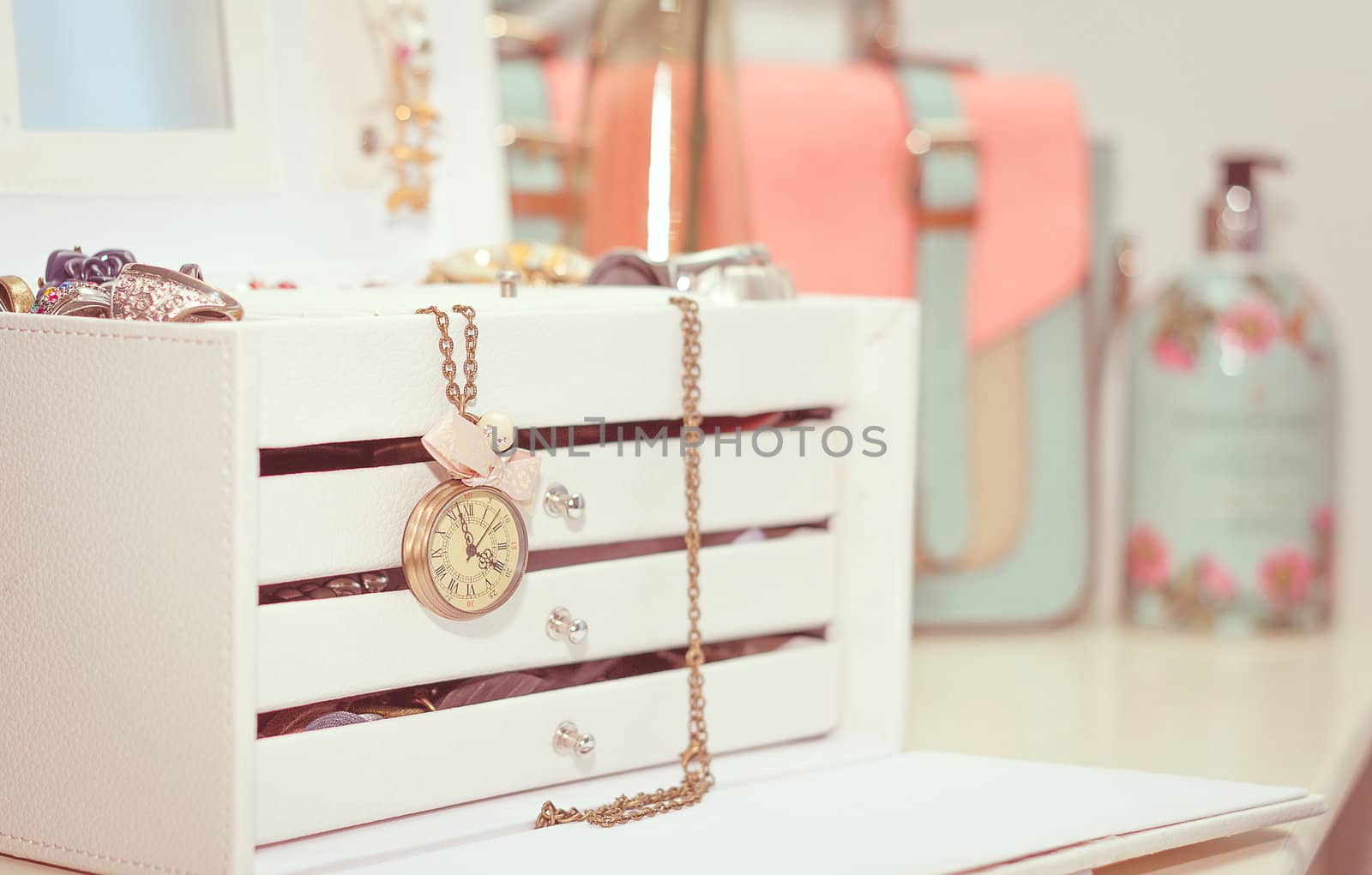White jewelry with drawers and vintage clock hanging and female complements in soft pastel colors