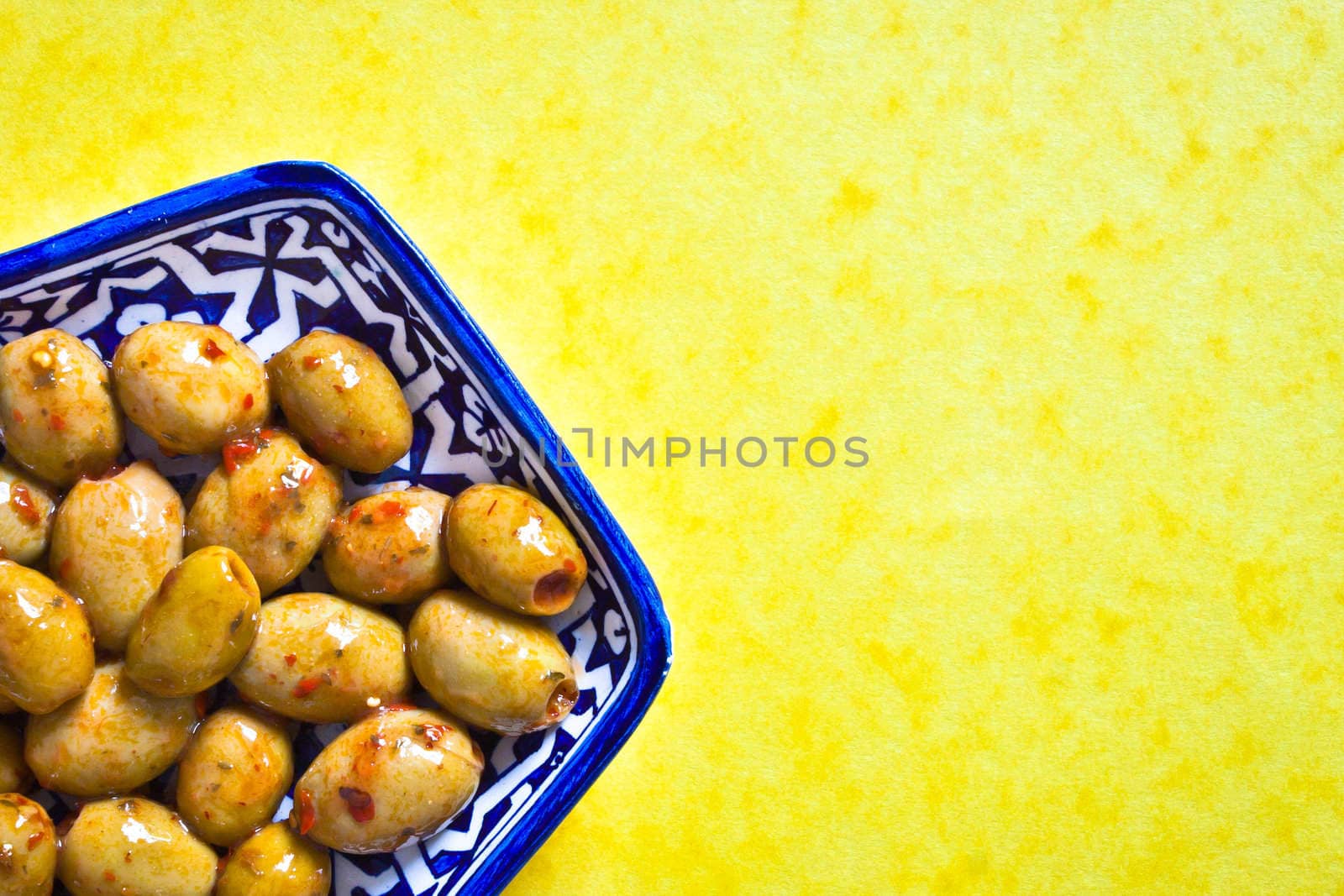 A dish of green olives with red chilli pepper