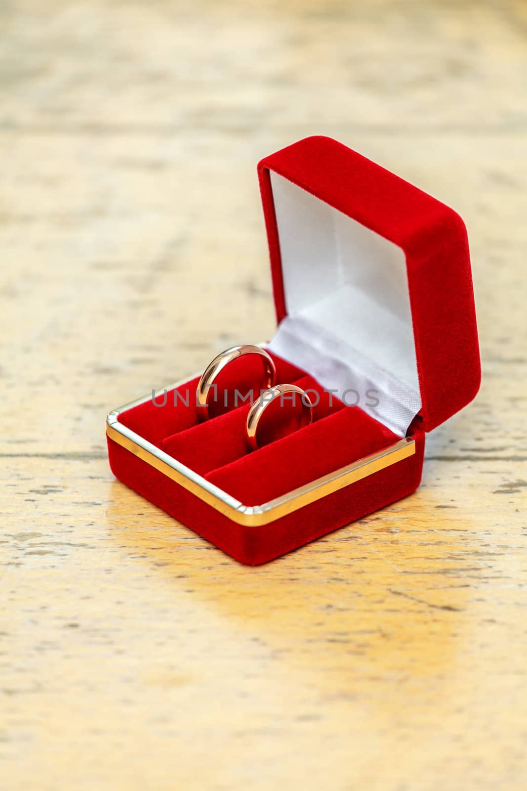 Two wedding rings in a box of red, lying on a wooden table