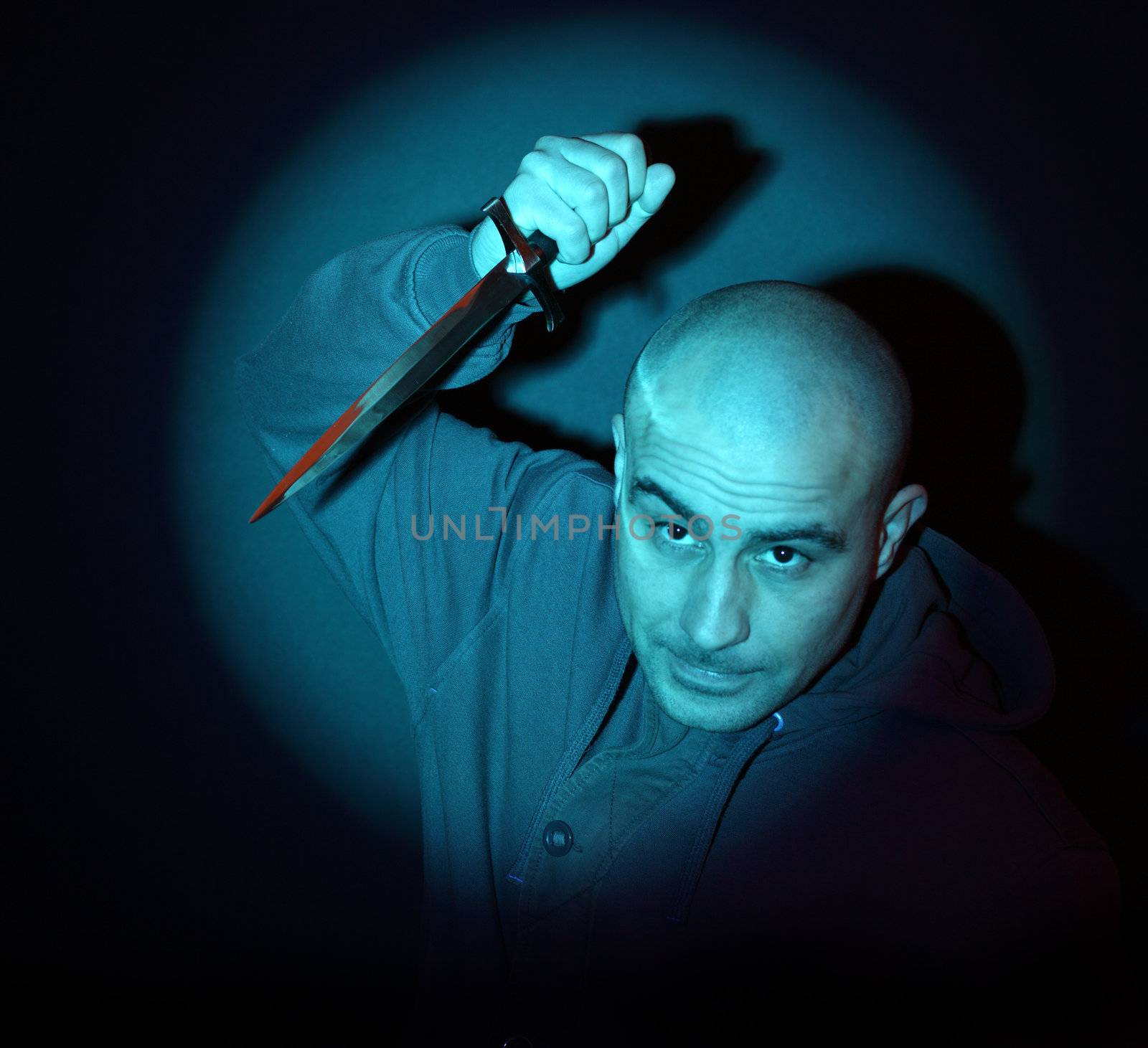 scary man with knife illuminated by a blue spotlight 