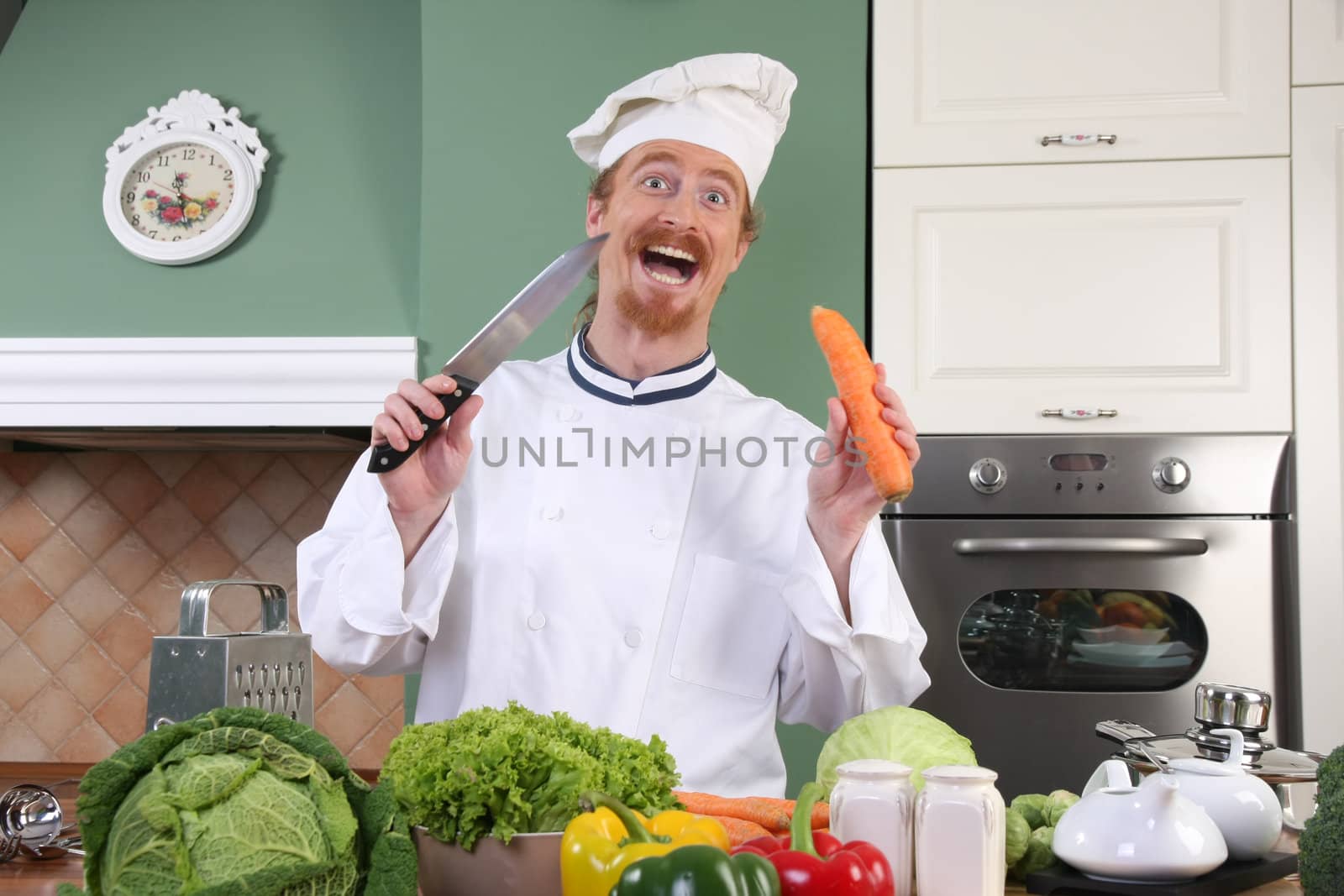 Funny young chef with carrot, preparing lunch in kitchen