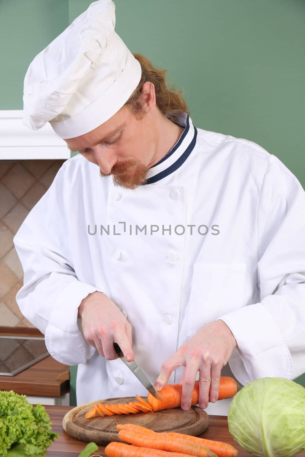 Young chef preparing lunch in kitchen by vladacanon
