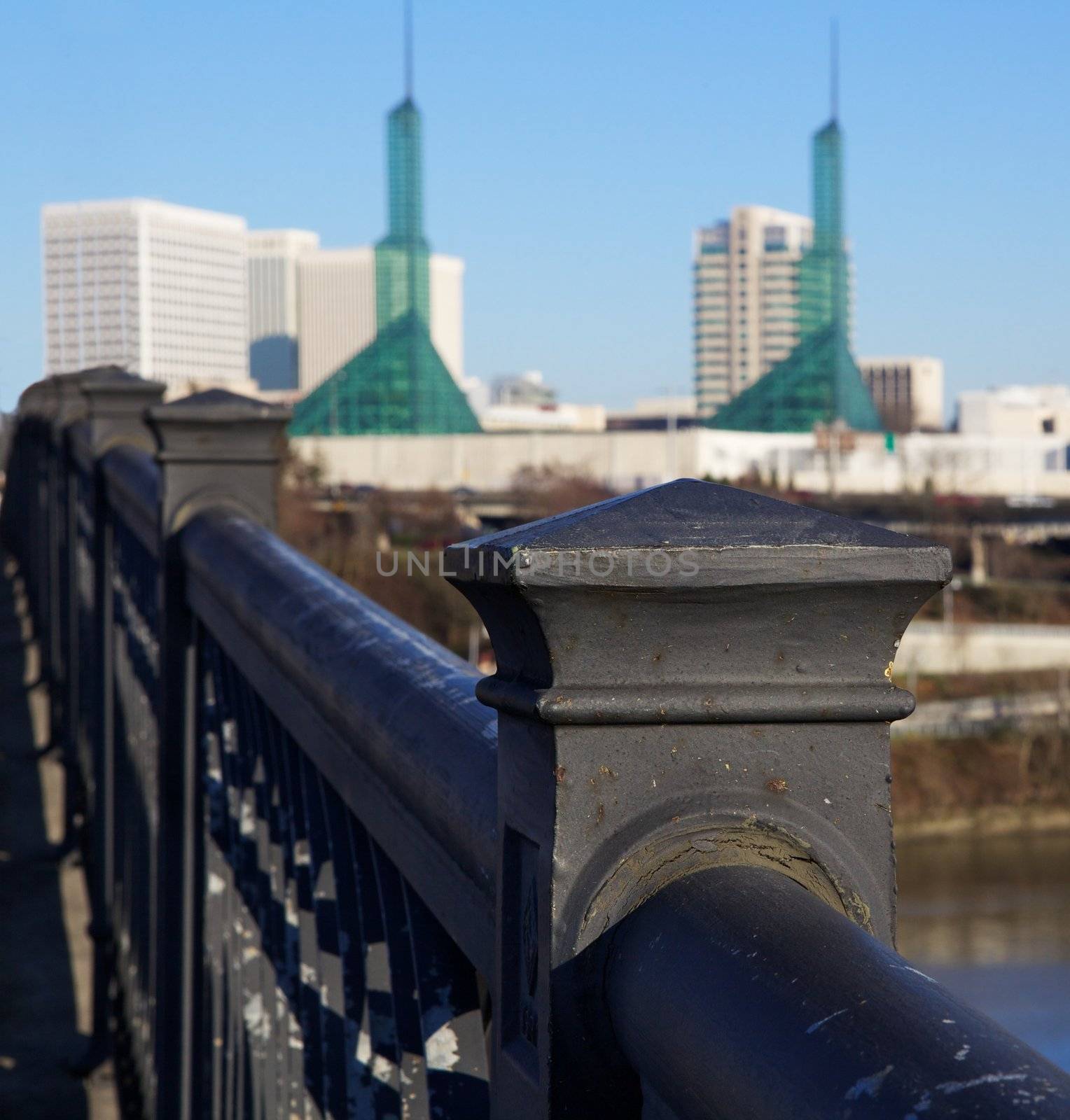 Close up of steel bridge railing over the willamette river looking towards a soft focus east Portland Oregon and convention center towers
