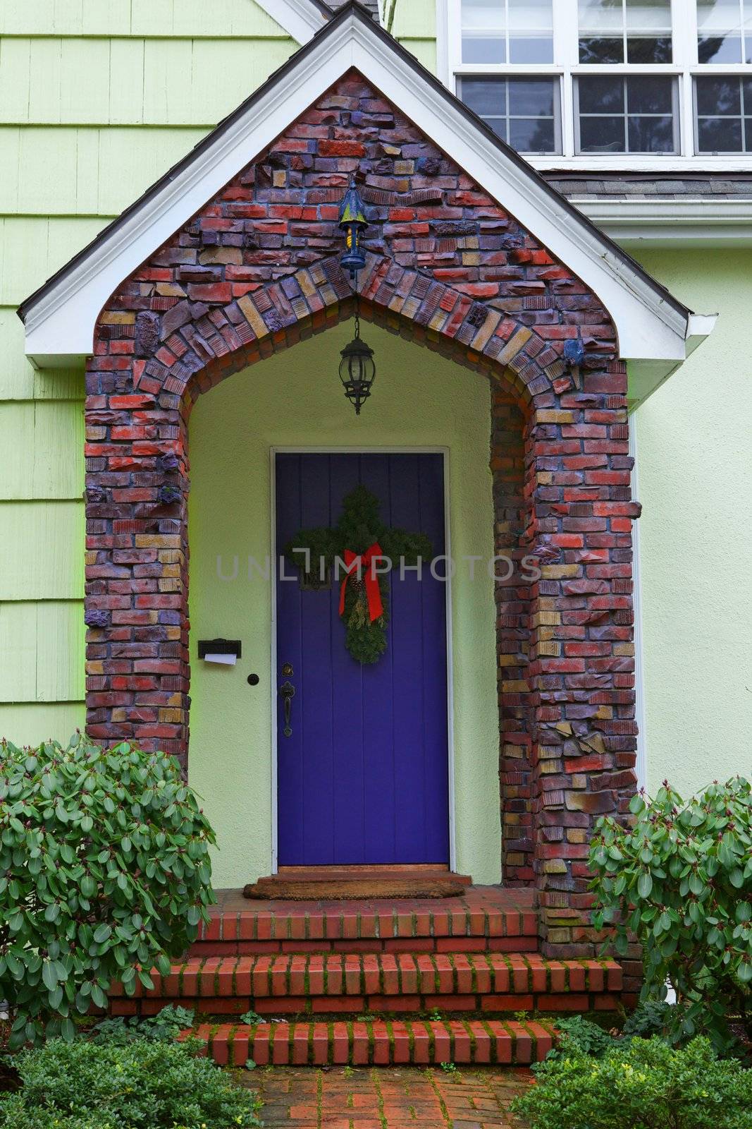 Multi-color Klinker brick borders a purple door of a yellow home