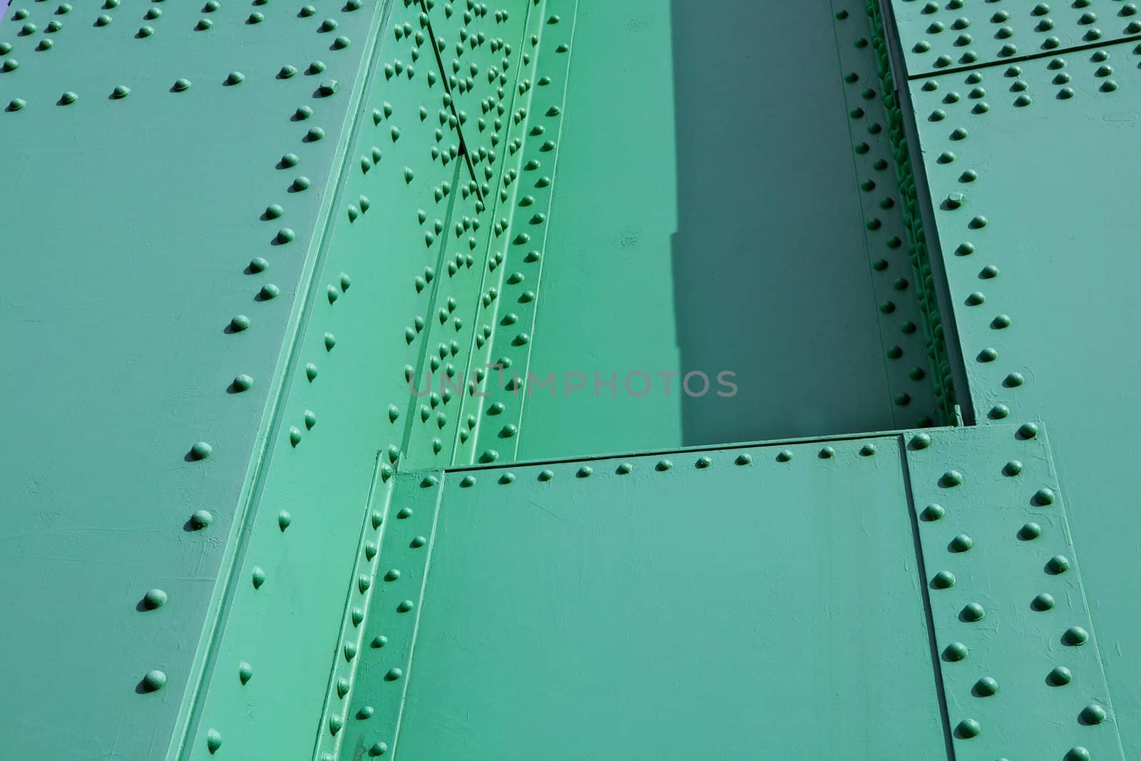 Abstract view of green painted steel beams and girders with many rivets