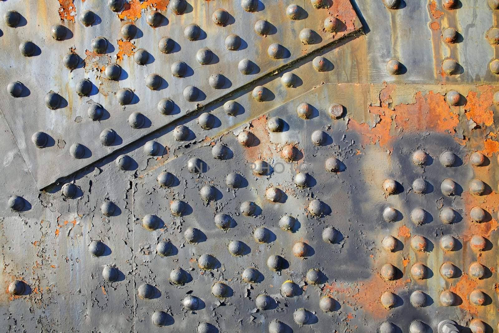 Old rusty rivets on large corroding steel plates of a train and auto Bridge