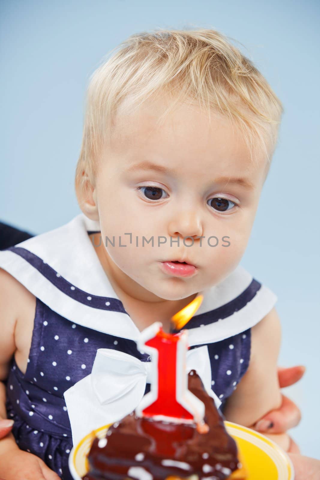 A little sweet girl with a cake and a candle in her first birthday.