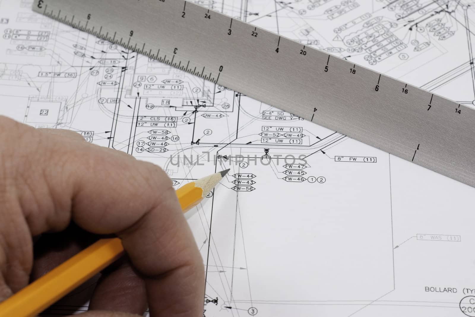 a hand holding a pencil with a scale on a set of plans for construction