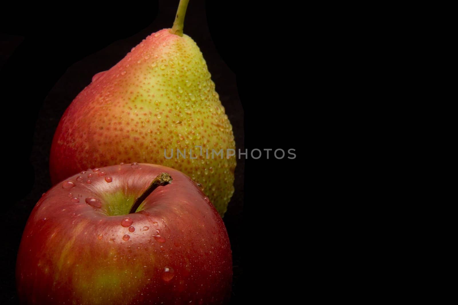 A juicy apple and pear with water drops on black