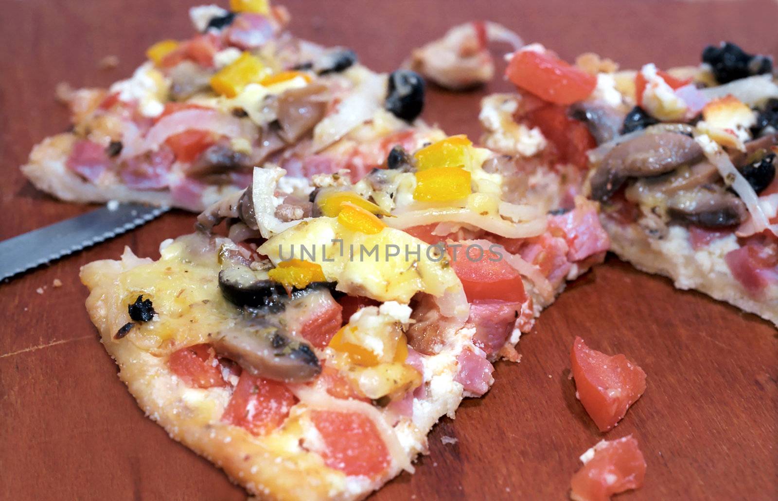 Parts of cutting pizza with ham, mushroom, tomatoes, paprika and cheese