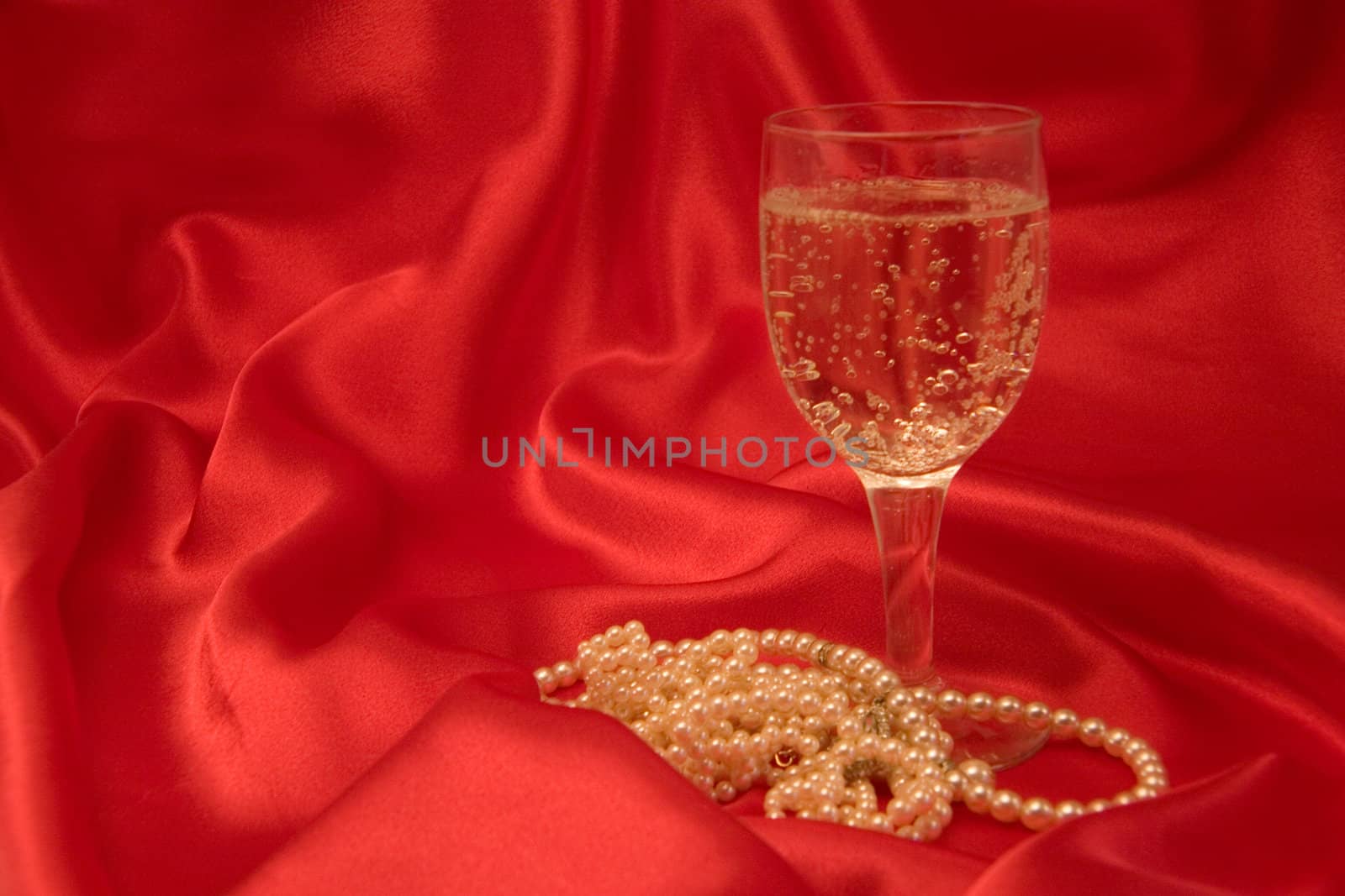 Sparkling champagne and pearls on red silk