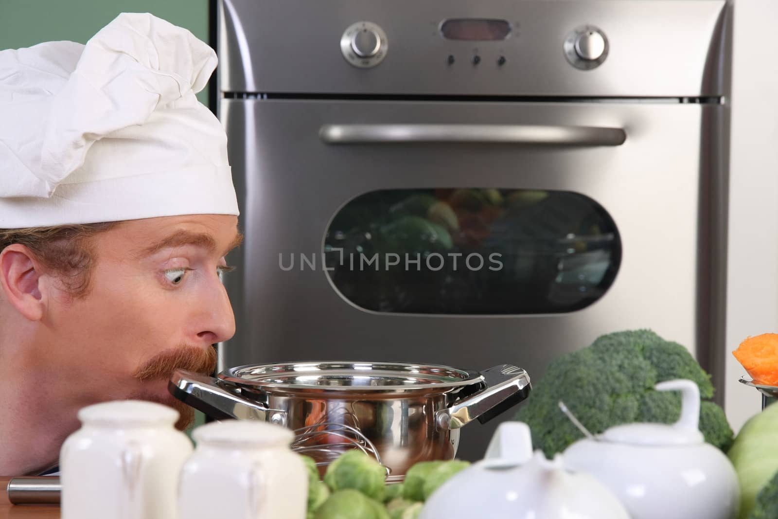 Funny young chef strange looking at pot by vladacanon