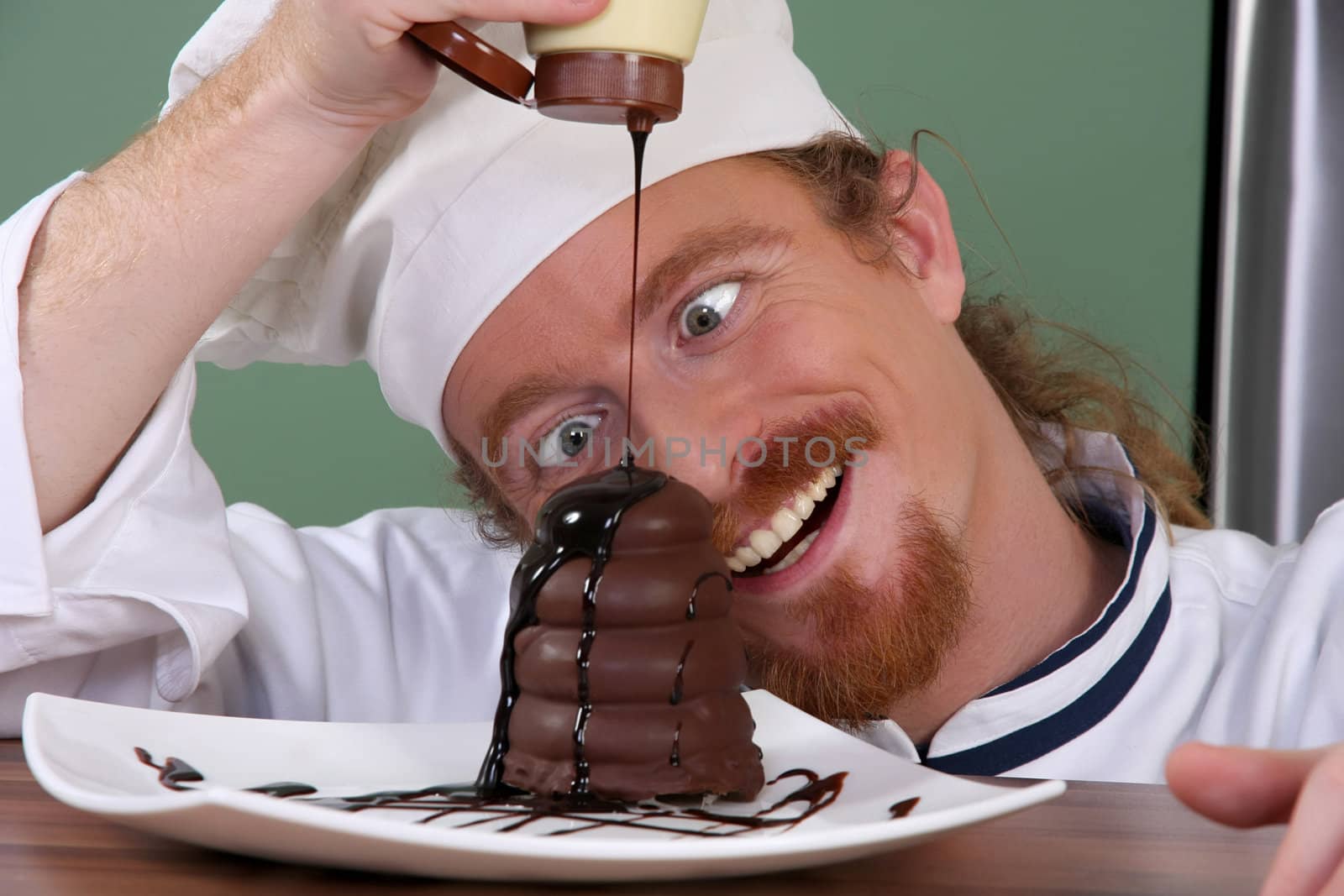 Funny young chef added chocolate sauce at piece of cake