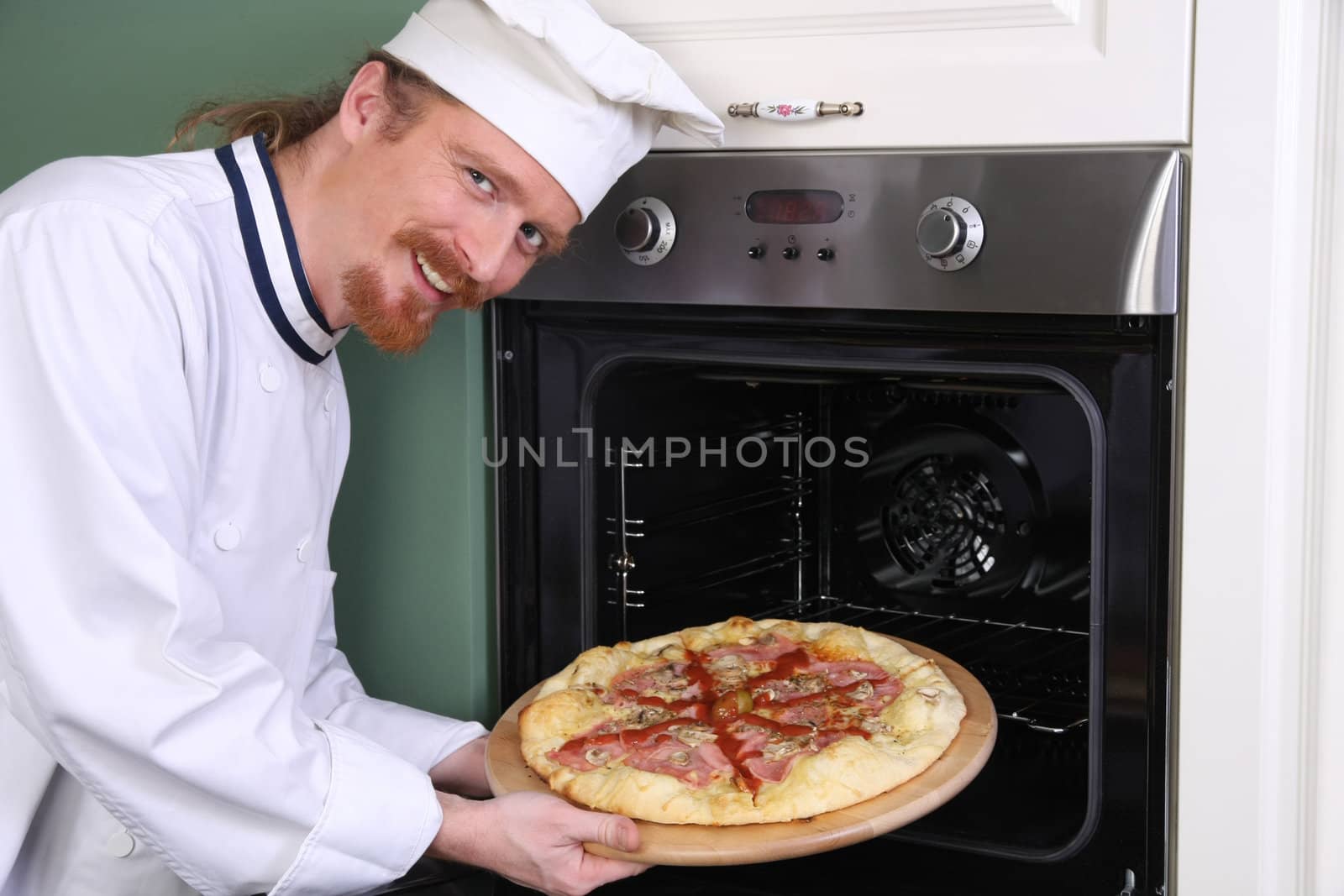 young chef with italian pizza in kitchen