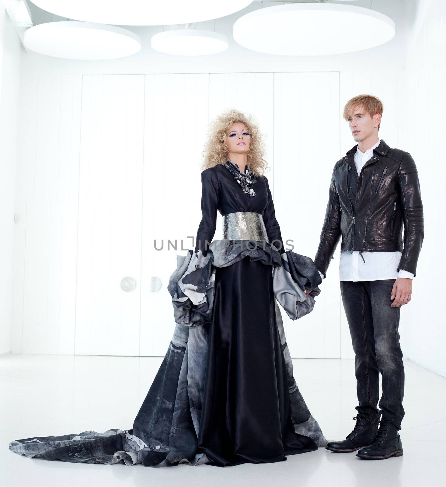 Black haute couture retro futurist couple in modern white hall with vampire inspiration