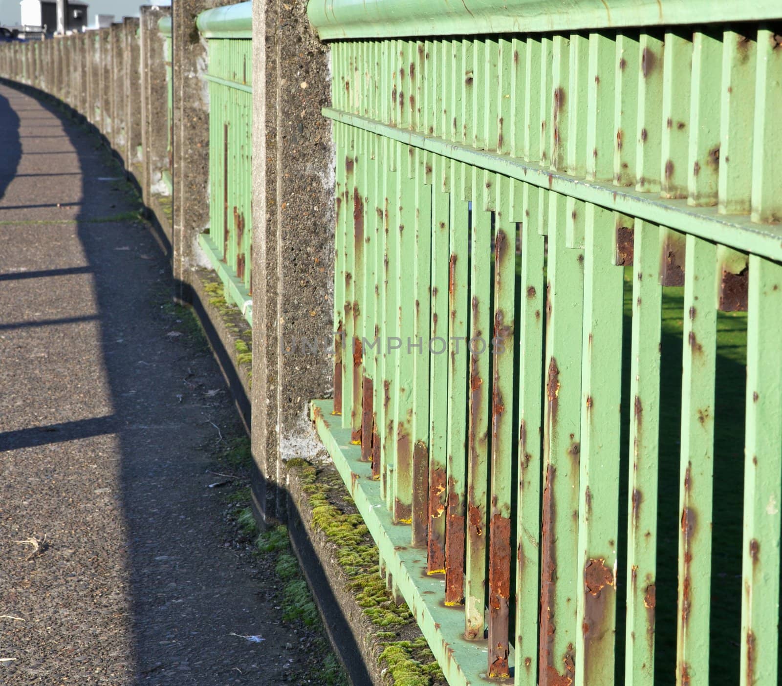 Green steel bridge railing that is rusted and worn