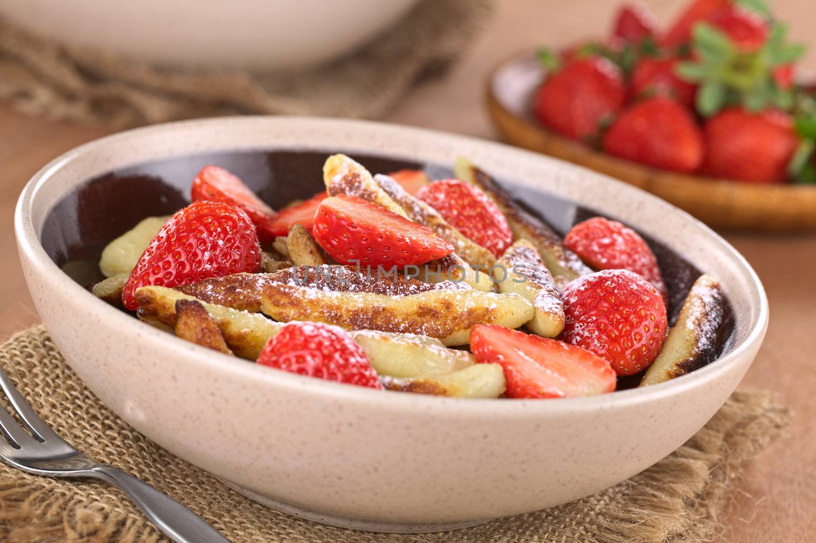 Schupfnudeln (Swabian potato noodles from Southern Germany) with fresh strawberries, cinnamon and sugar powder (Selective Focus, Focus on the front of the three strawberry pieces in the middle of the bowl) 