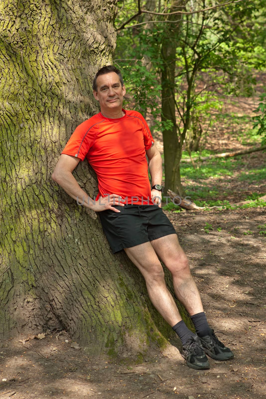 Smiling Middle Age Man Runner Relaxing against a Tree