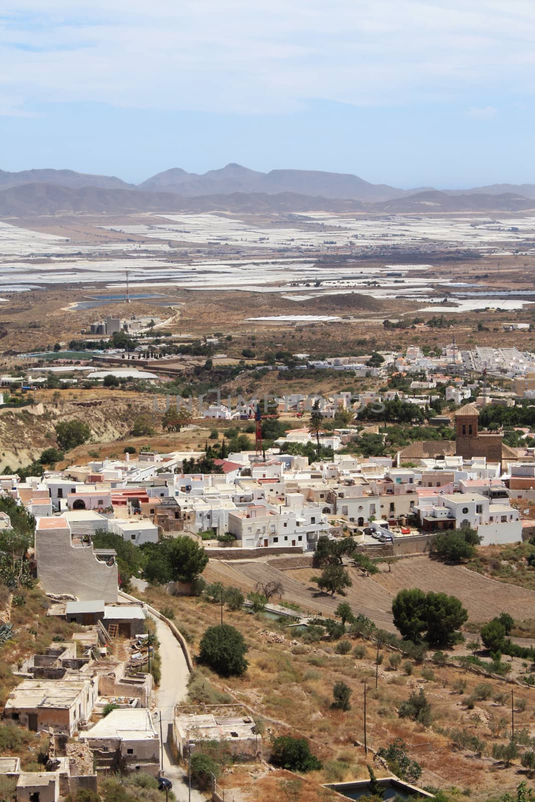 Bird's eye view of Nijar, a typical whitewashed Andalusian village in the province of Almeria, Spain, with greenhouses in the background.