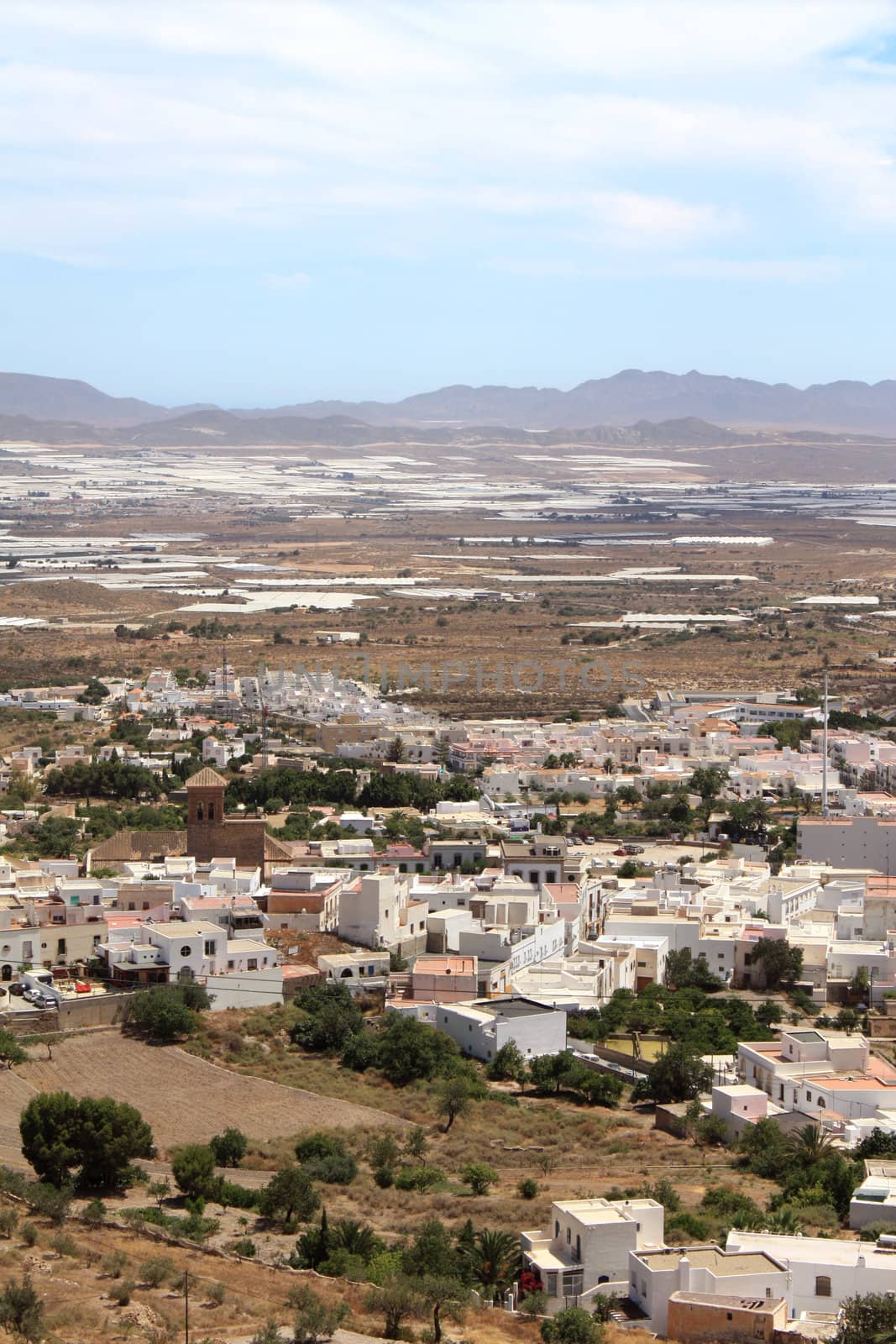 Bird's eye view of Nijar, a typical whitewashed Andalusian village in the province of Almeria, Spain, with greenhouses in the background.