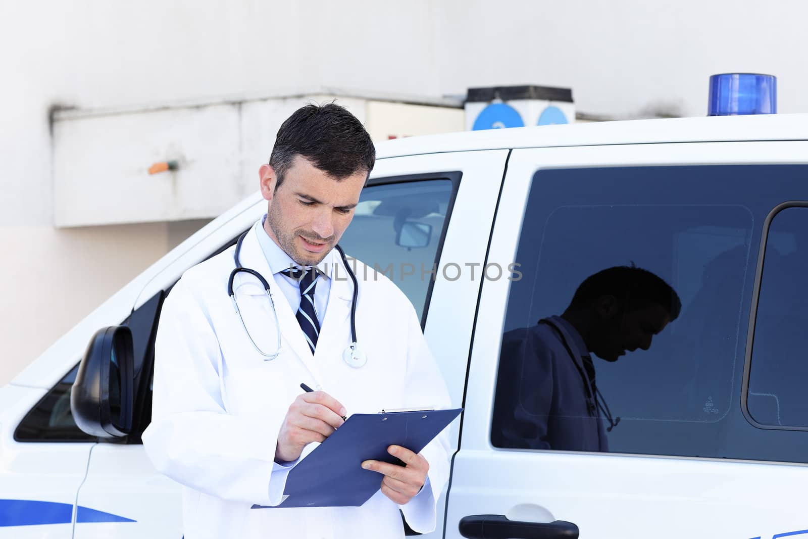 handsome doctor writing in front of ambulance