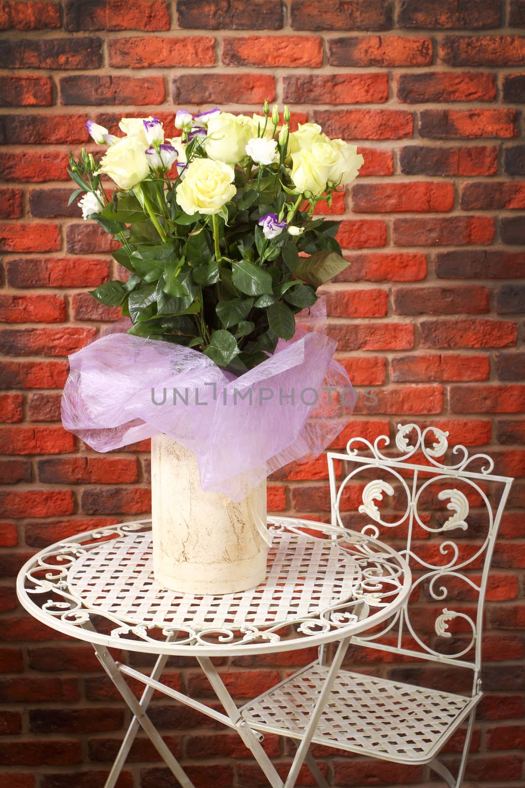 Bunch of flowers on a metal shod table against a wall from a red brick