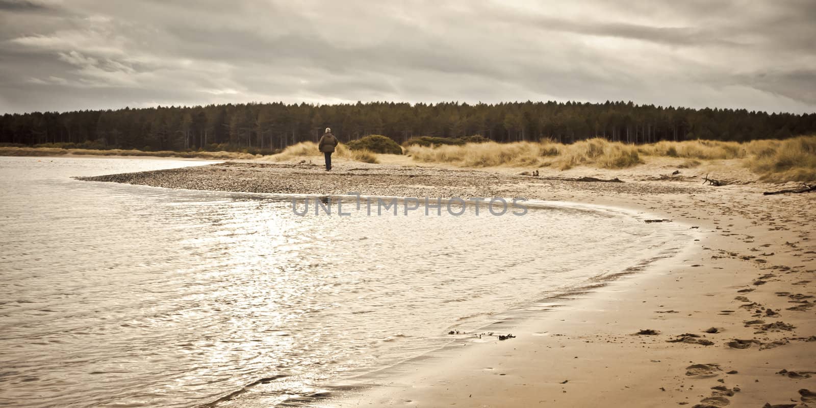 A lone pedestrian walking along Findhorn Beach