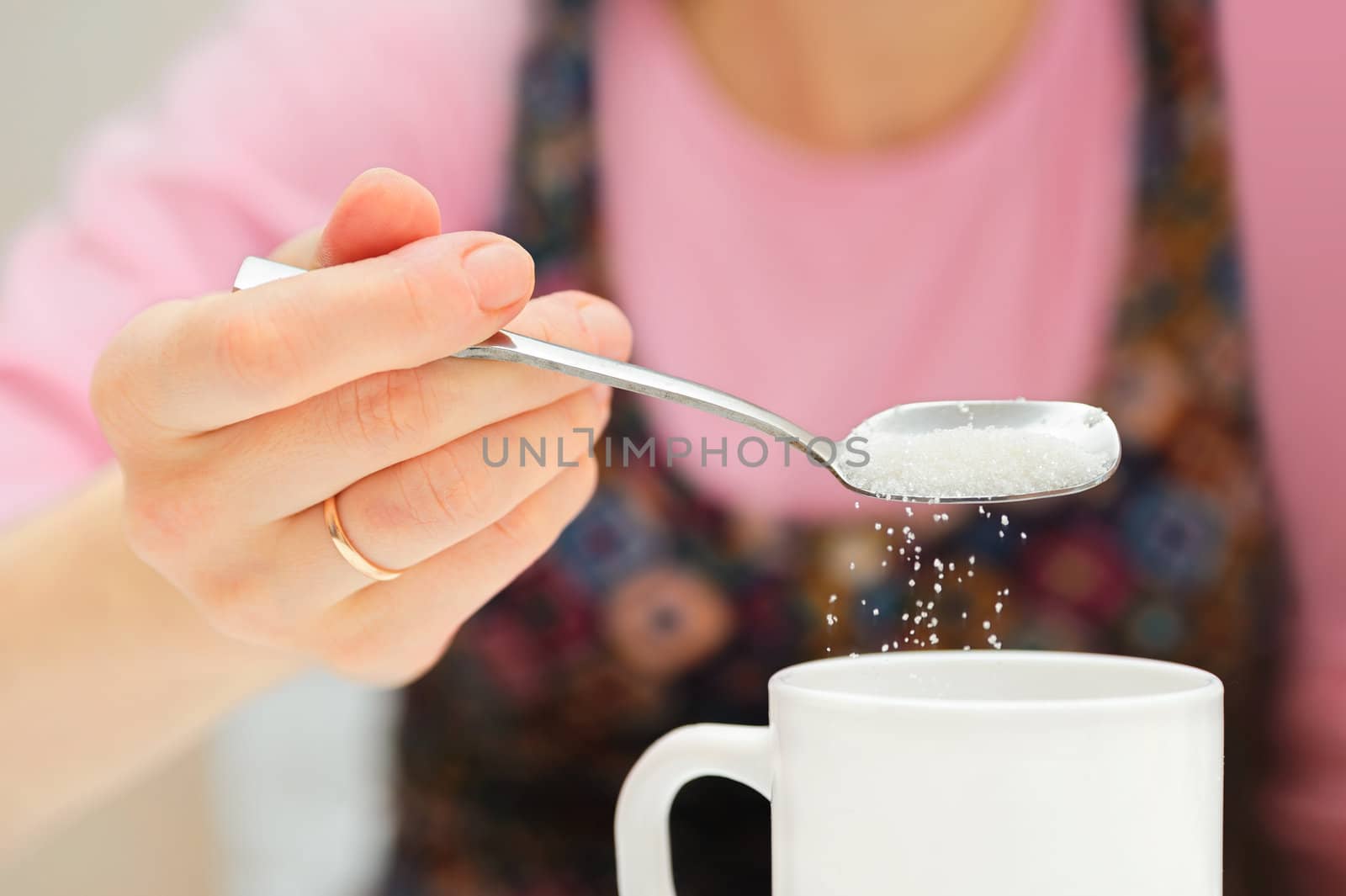 girl holds a spoon and strews sugar to mug by docer2000