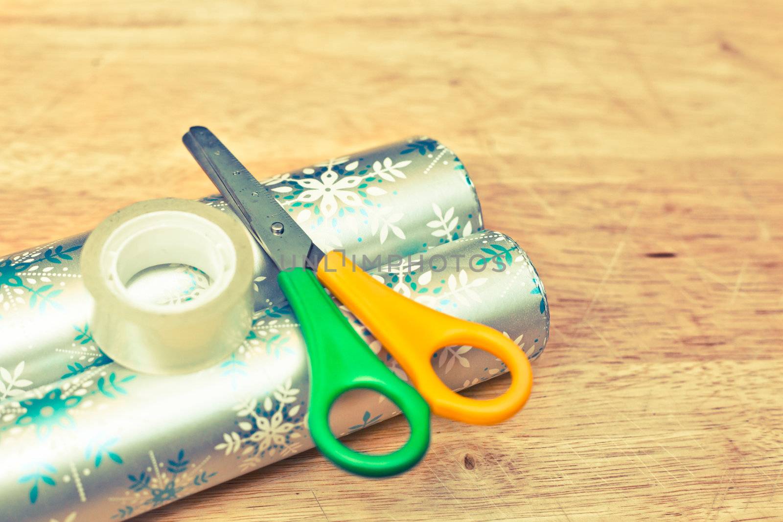 Scissors, tape and wrapping paper on a wooden table