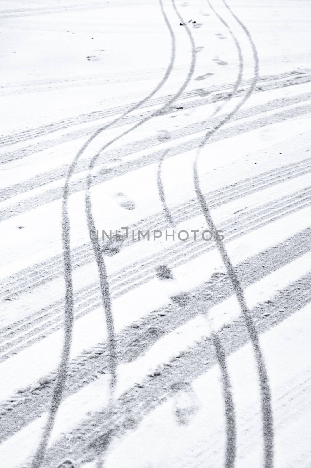 Car and bike tyre tracks and footprints on a snowy road