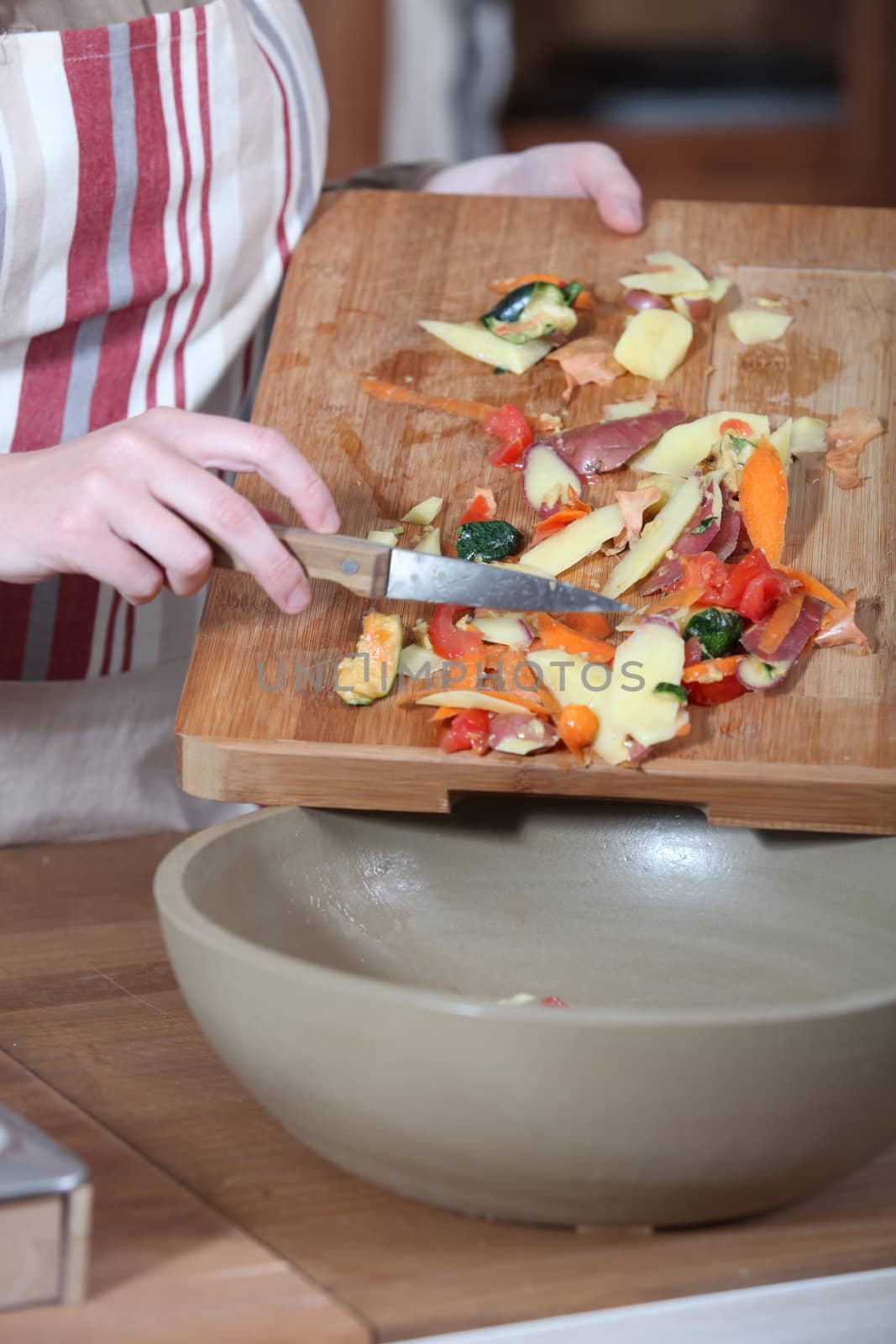Women removing vegetables peeling from chopping board by phovoir