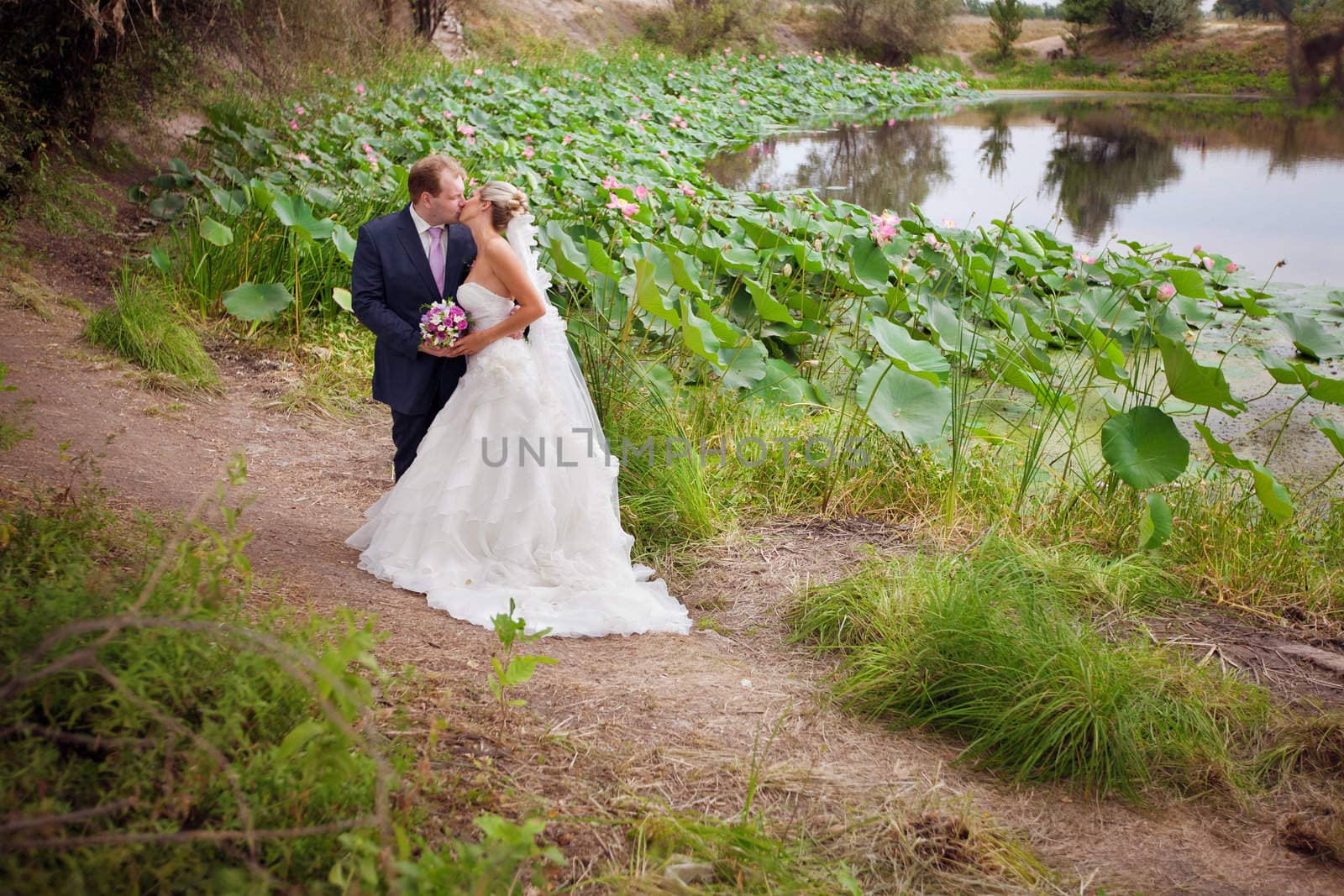 kissing bride and groom near the lotus pond