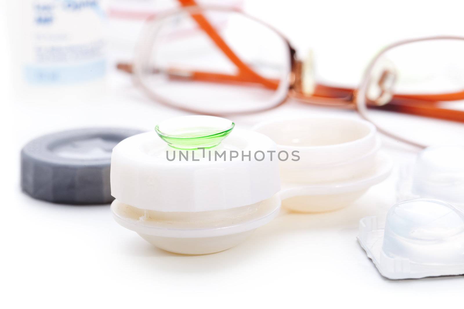 Close-up of green contact lenses in container with solution. 
 by motorolka