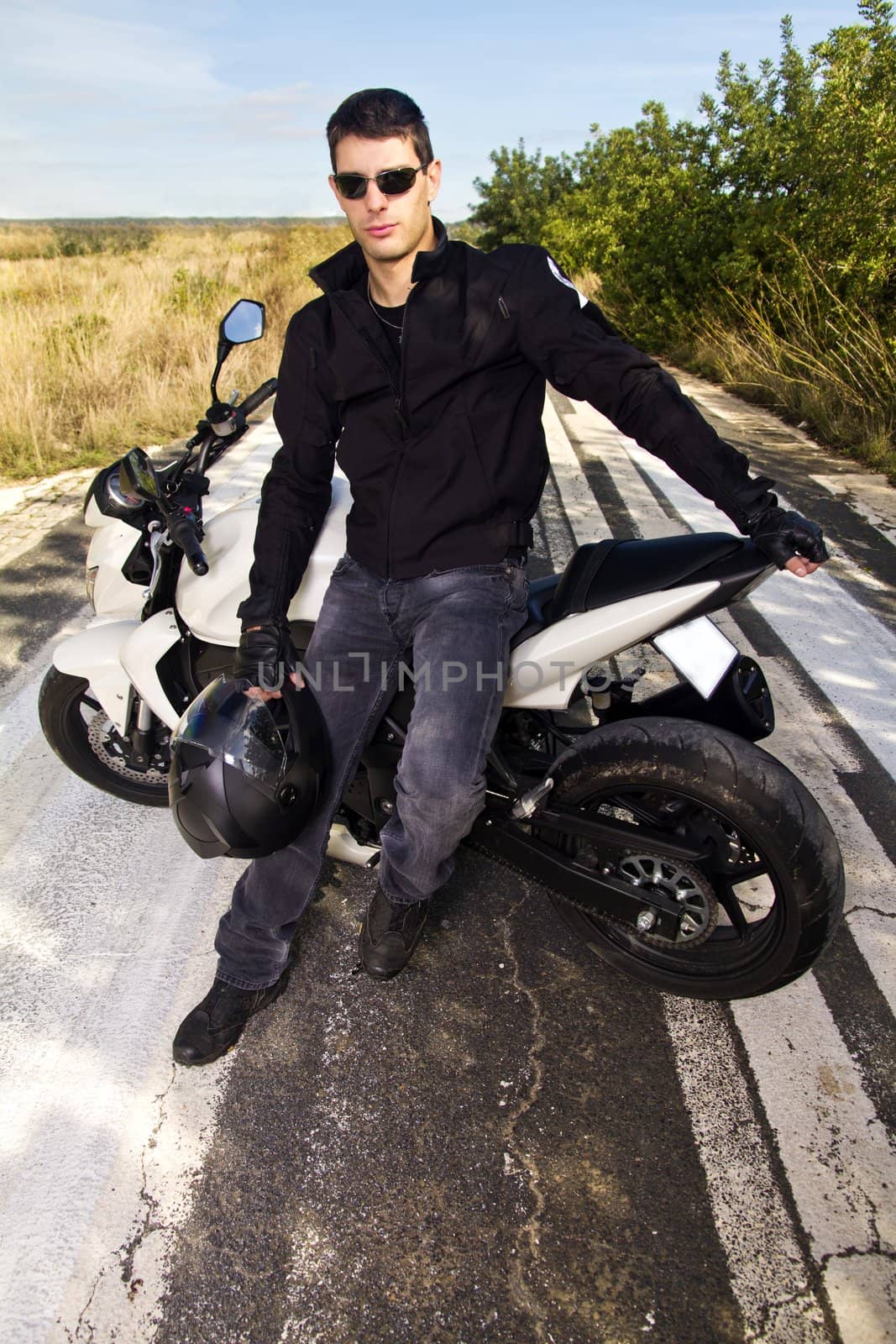 View of a man with a motorcycle on a asphalt road.