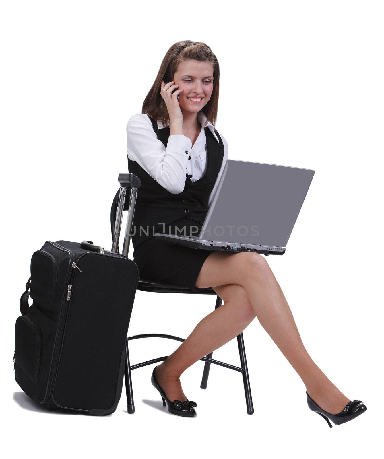 Young traveler businesswoman working on a laptop while is calling by phone next to her suitcase.