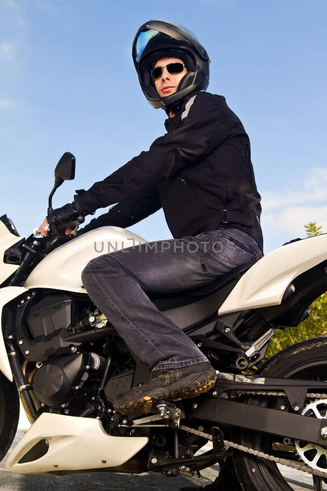 View of a man with a motorcycle on a asphalt road.