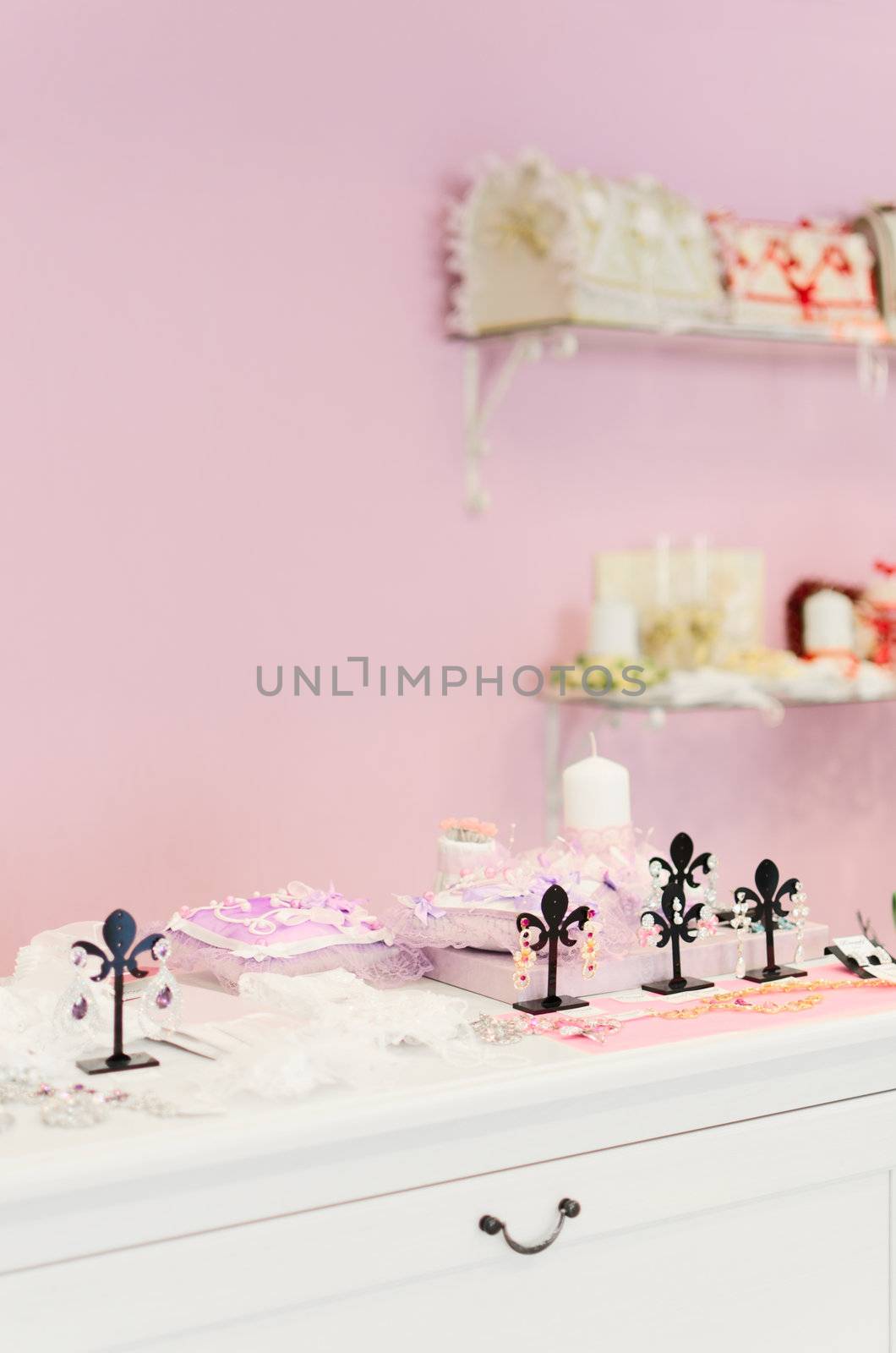 Wedding store background. Bridal bijouterie. Pink wall and different stuff on glass shelfs