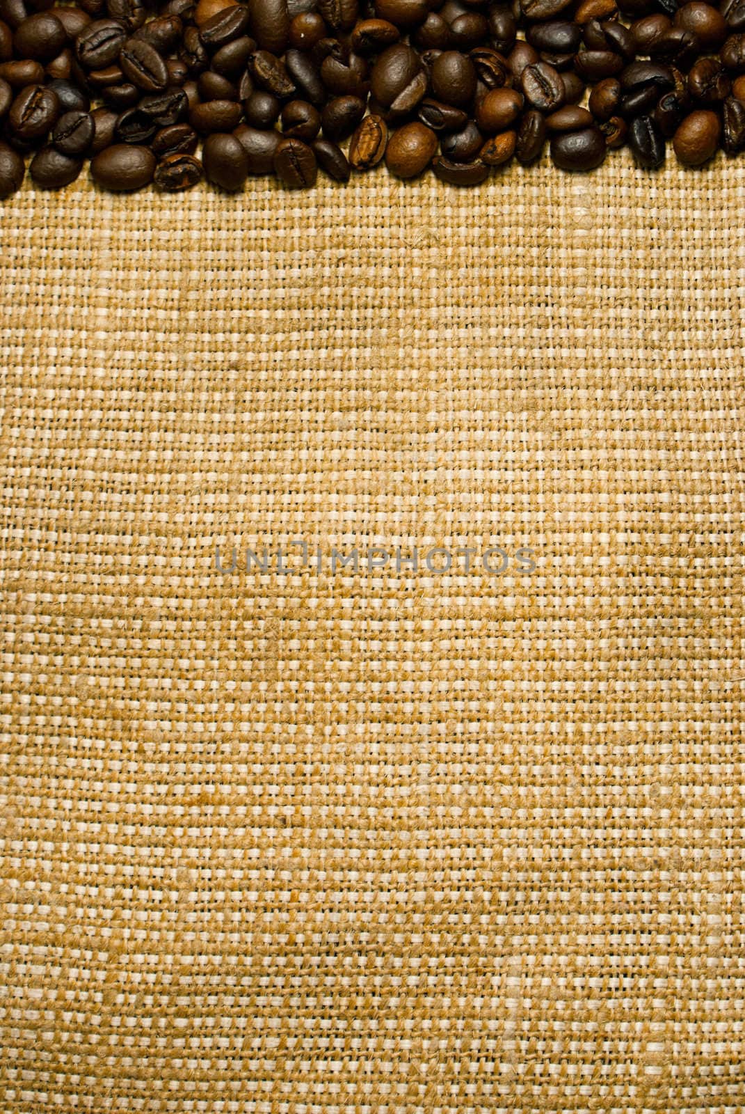 Background of the roasted coffee beans on a burlap piece