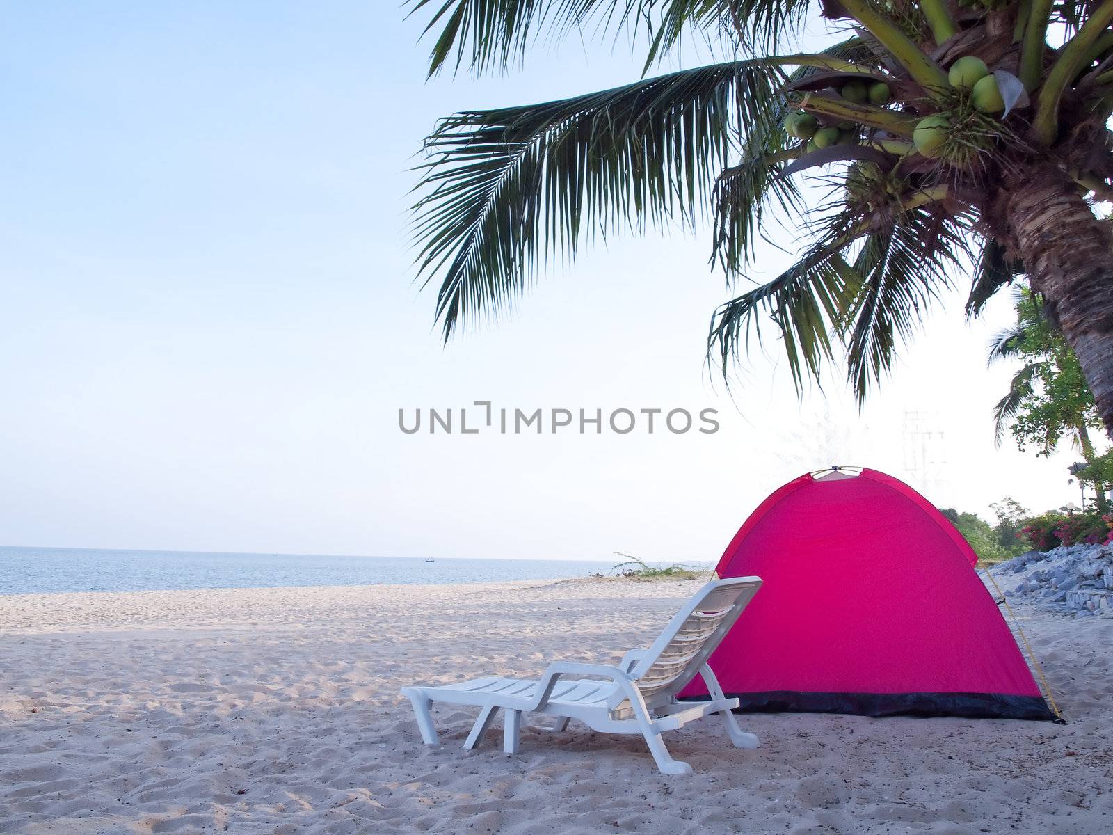 Tent on tropical beach with deckchair in shady of coconut