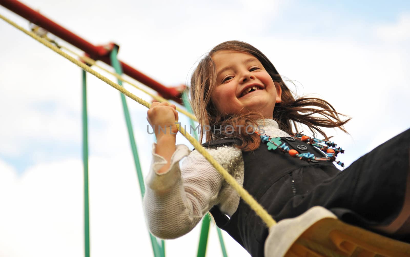 happy young girl on her swing on a cloudy sky