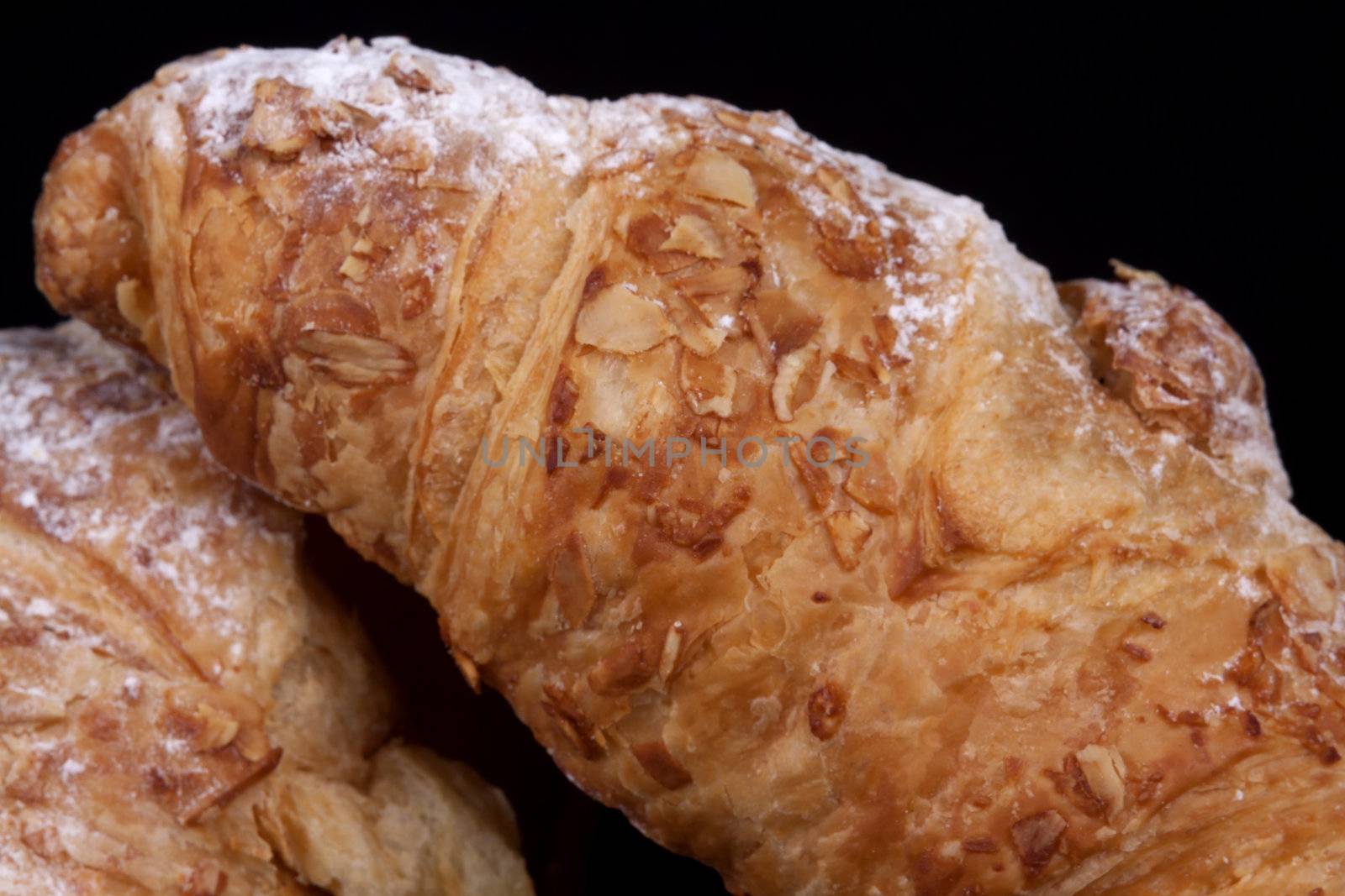 fresh almond croissant isolated on a black background