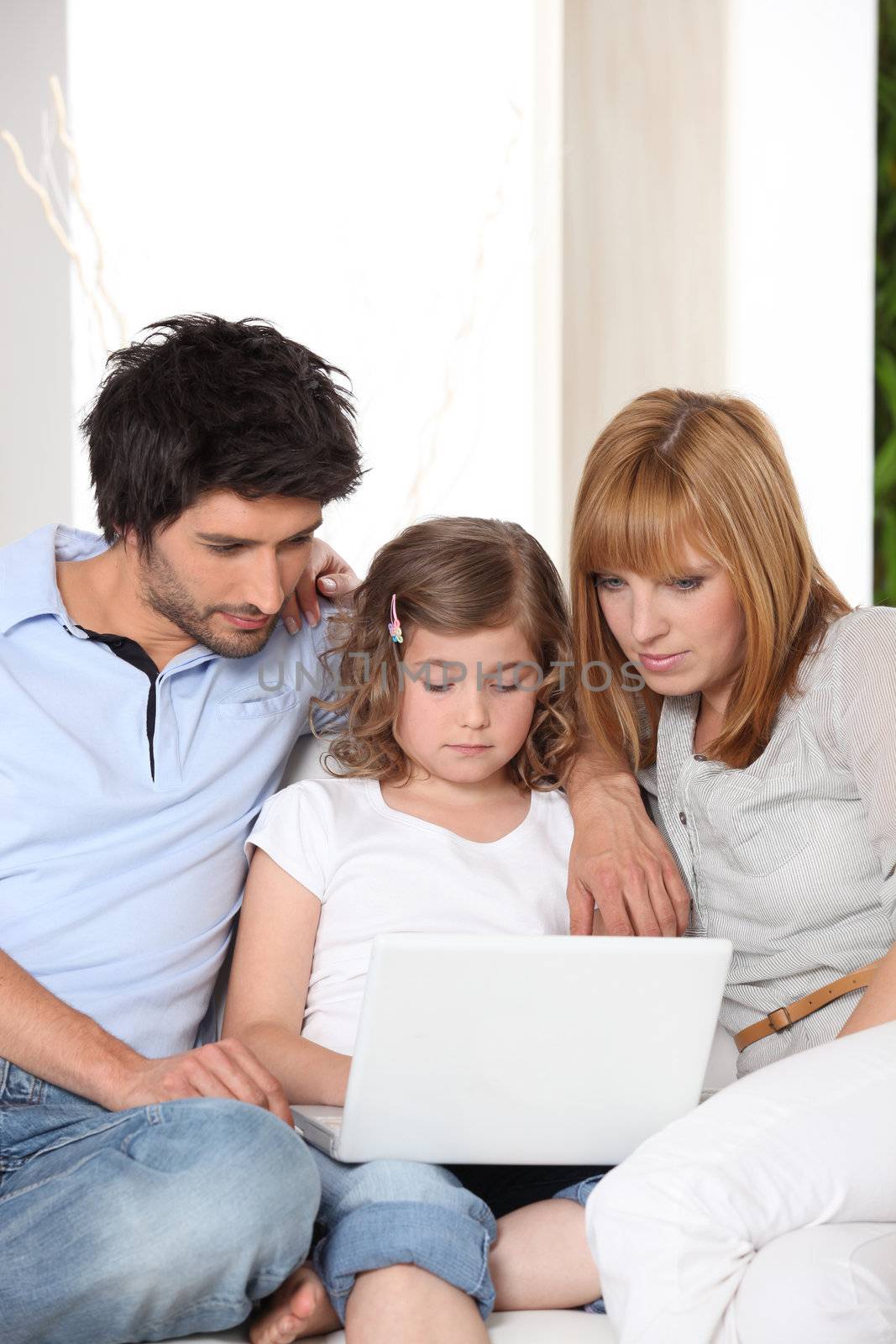 couple with daughter and laptop on sofa