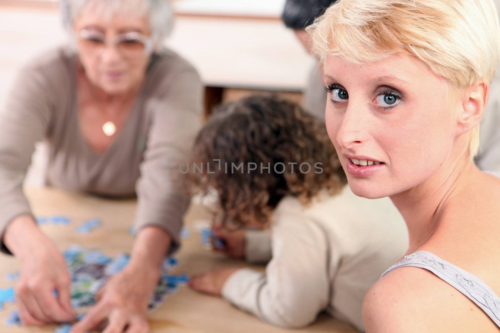 Family sat by table playing game by phovoir